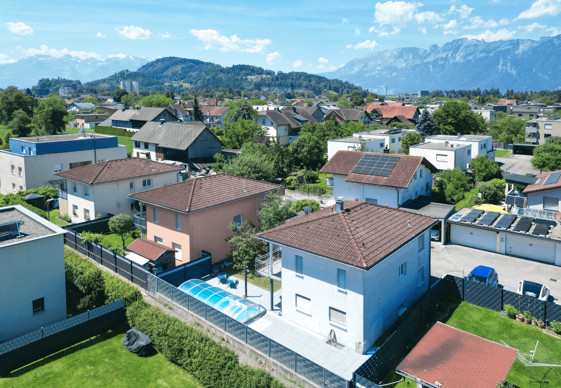 Luftaufnahme einer Wohnsiedlung mit Einfamilienhäusern und Bergblick.