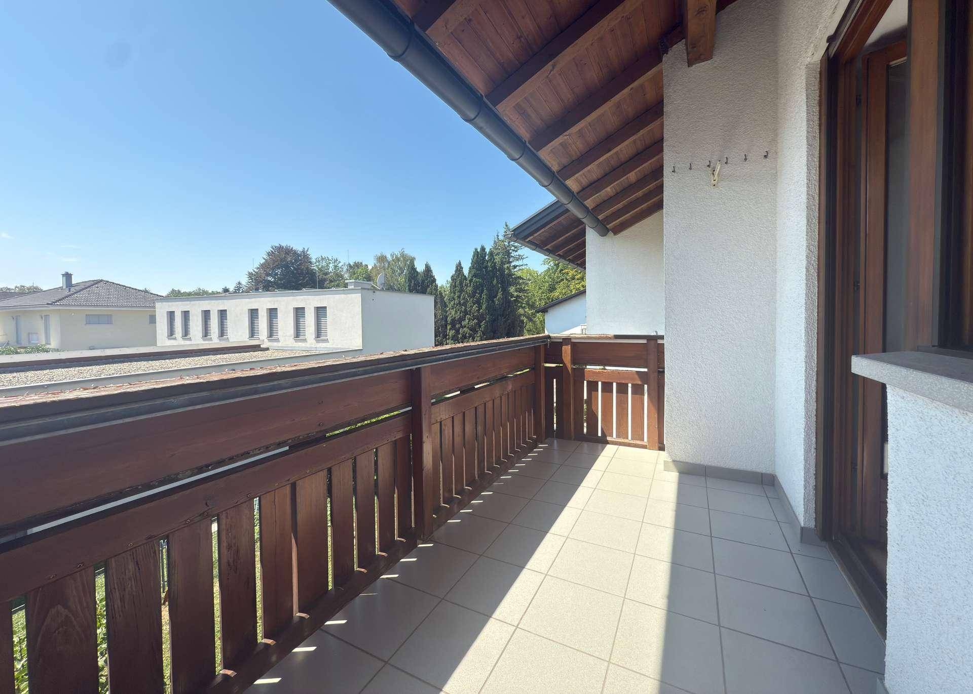 Sonniger Balkon mit Fliesenboden und Holzgeländer, ideal für entspannte Stunden im Freien.