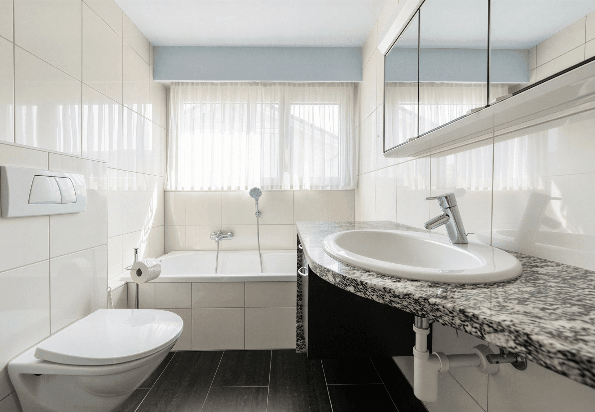 Helles Badezimmer mit Badewanne, Granitwaschtisch und großem Spiegel.