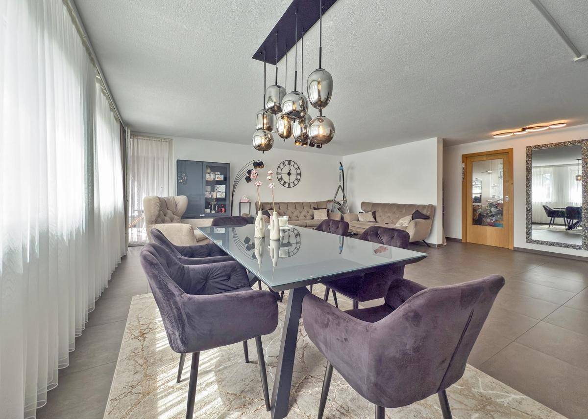 Eleganter Essbereich mit großem Glastisch, Samtstühlen und moderner Hängelampe.