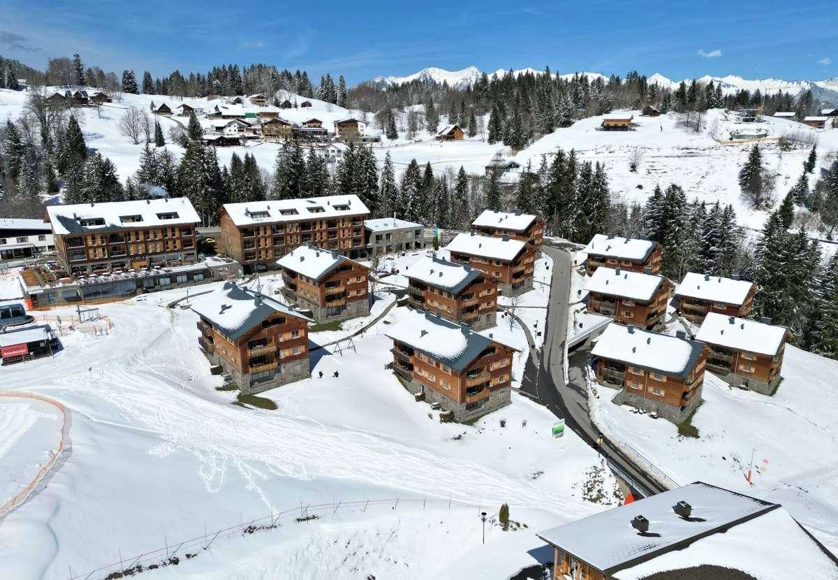 Winterliche Ansicht einer Wohnanlage in den verschneiten Bergen.