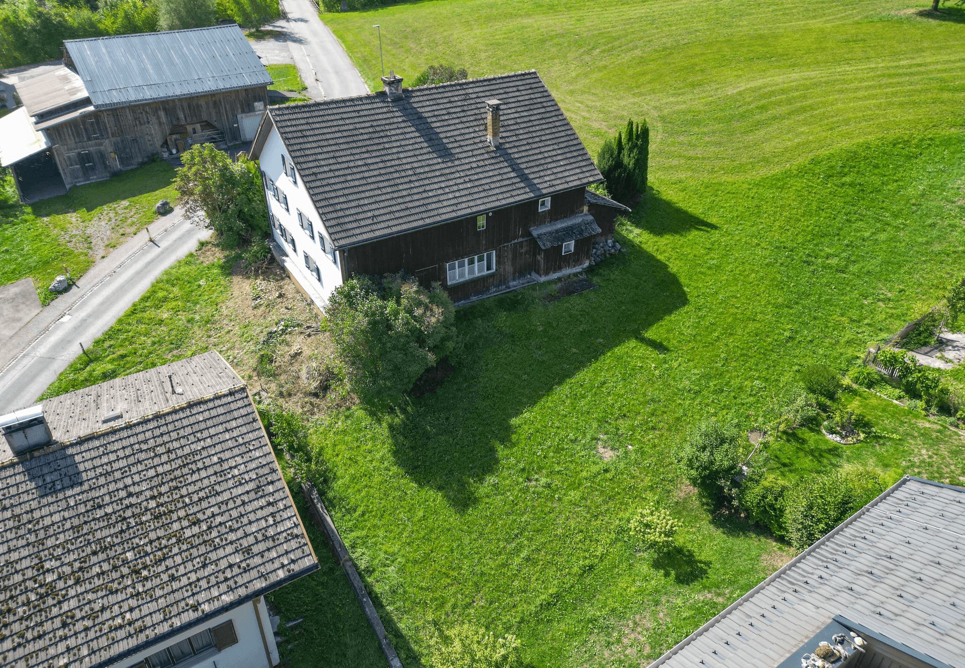 Vogelperspektive des Hauses mit großem Garten, umgeben von weiteren Gebäuden und grünen Wiesen.