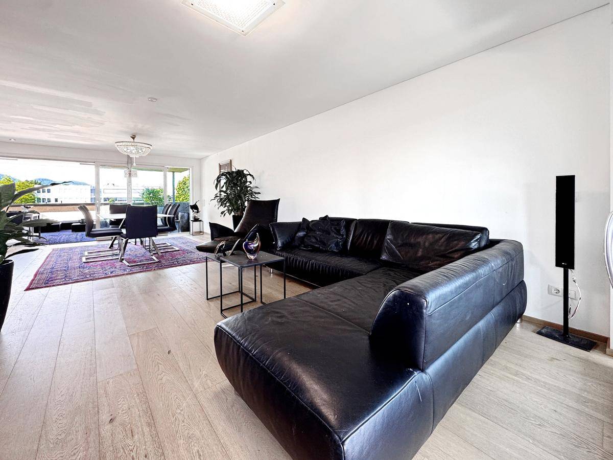 Heller offener Wohn-Essbereich mit Ledersofa, Holzboden und Zugang zur Terrasse.