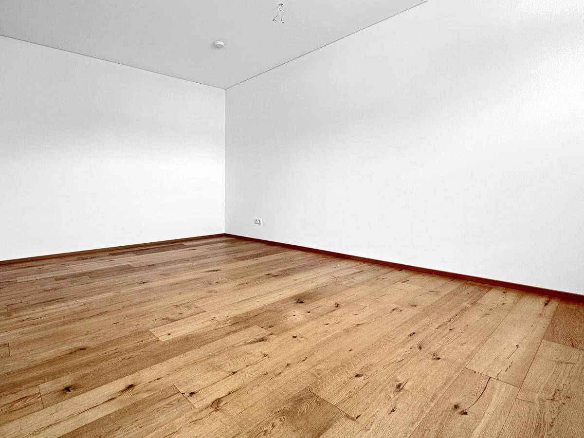 Leerer Raum mit Holzboden und weißen Wänden, bereit für individuelle Gestaltung.