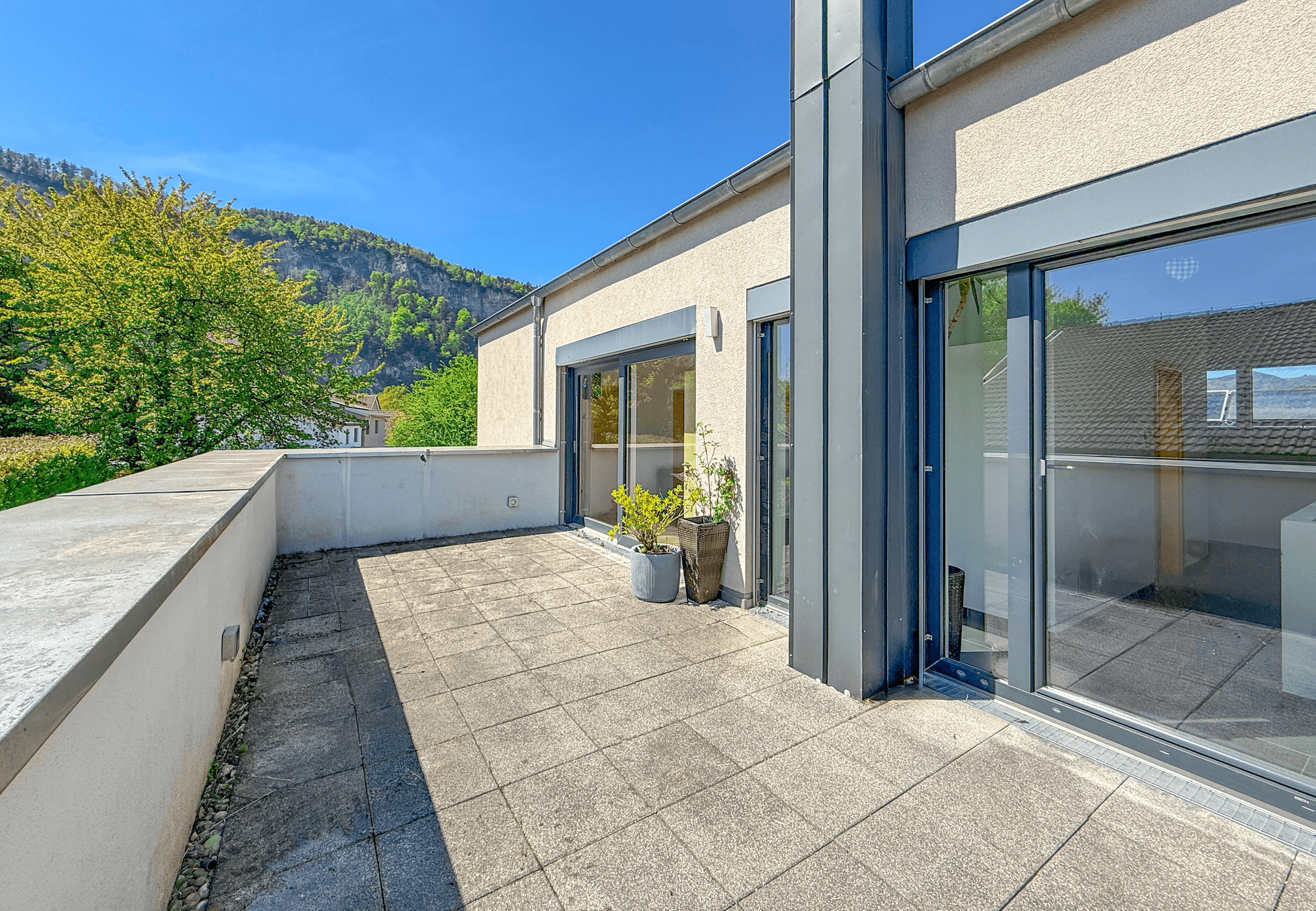 Geräumige Dachterrasse mit Fliesenboden und weitem Blick auf die umliegende Berglandschaft.