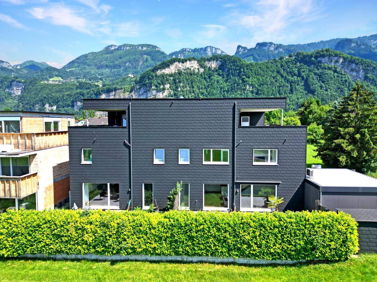 Ansicht der modernen Gebäudefassade mit dunklen Schindeln und großen Fenstern.