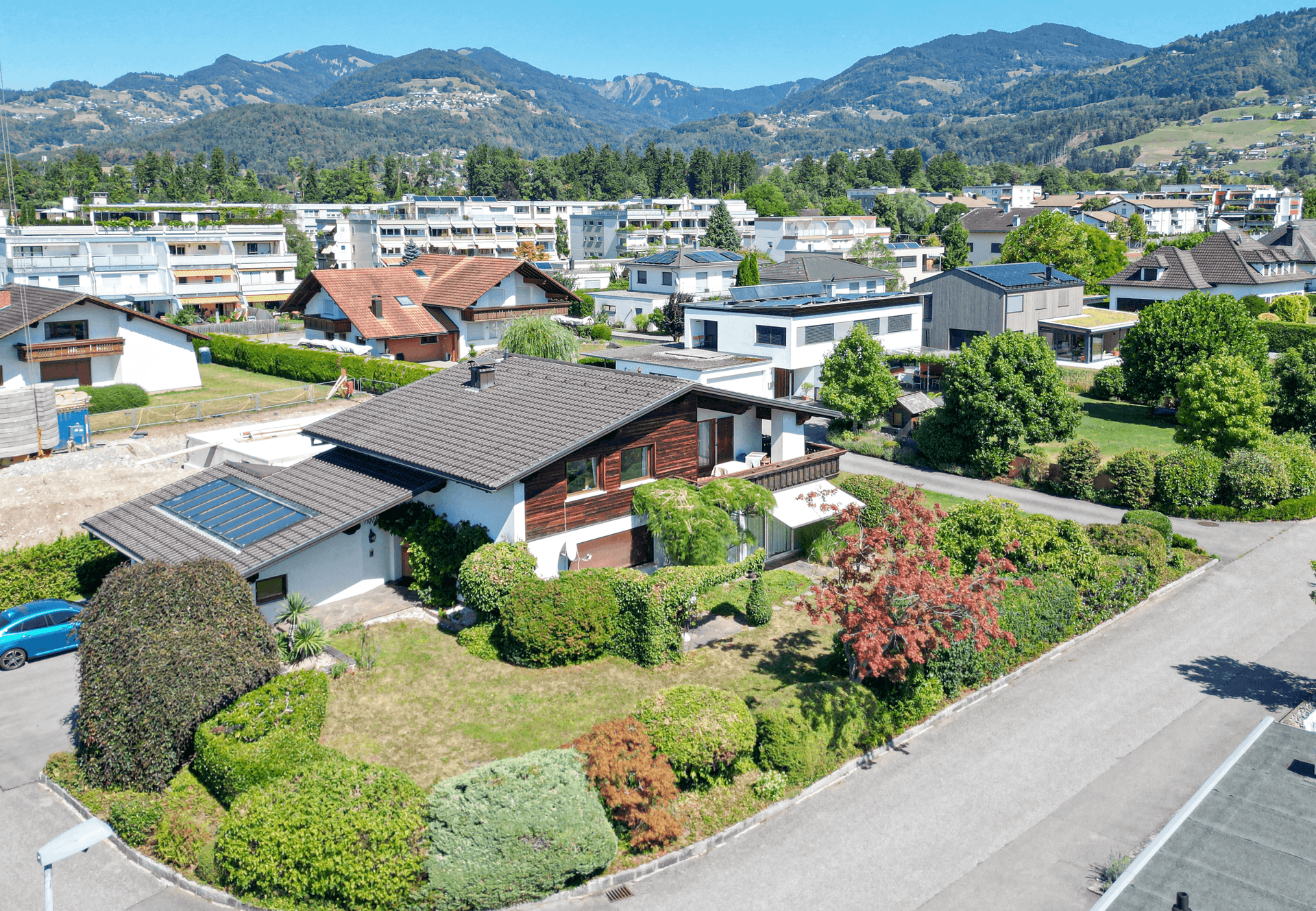 Luftaufnahme des Hauses mit gepflegtem Garten und Bergblick in einer Wohnsiedlung.