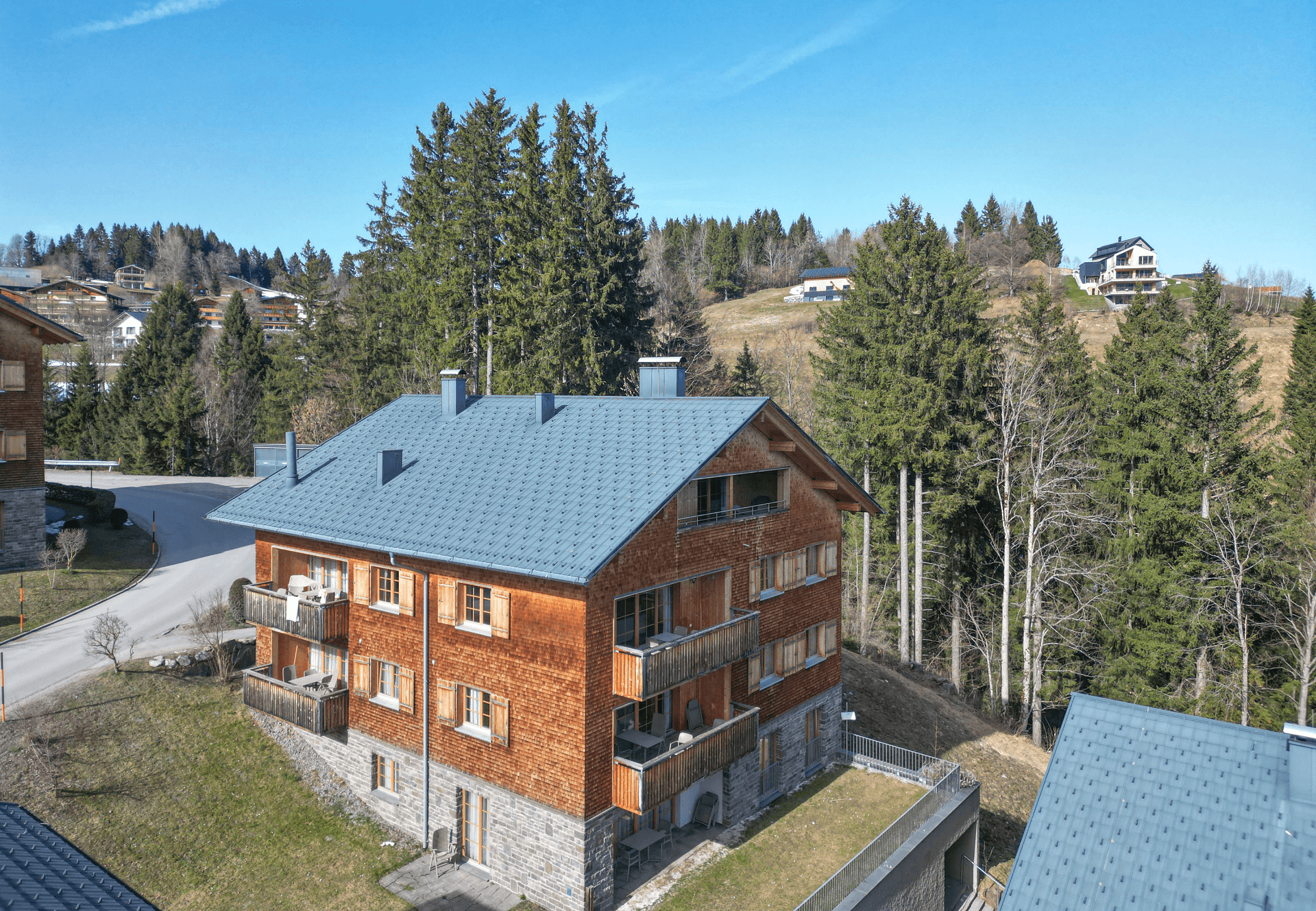 Attraktives Holzhaus mit Schindelfassade und Satteldach, eingebettet in eine grüne Berglandschaft.