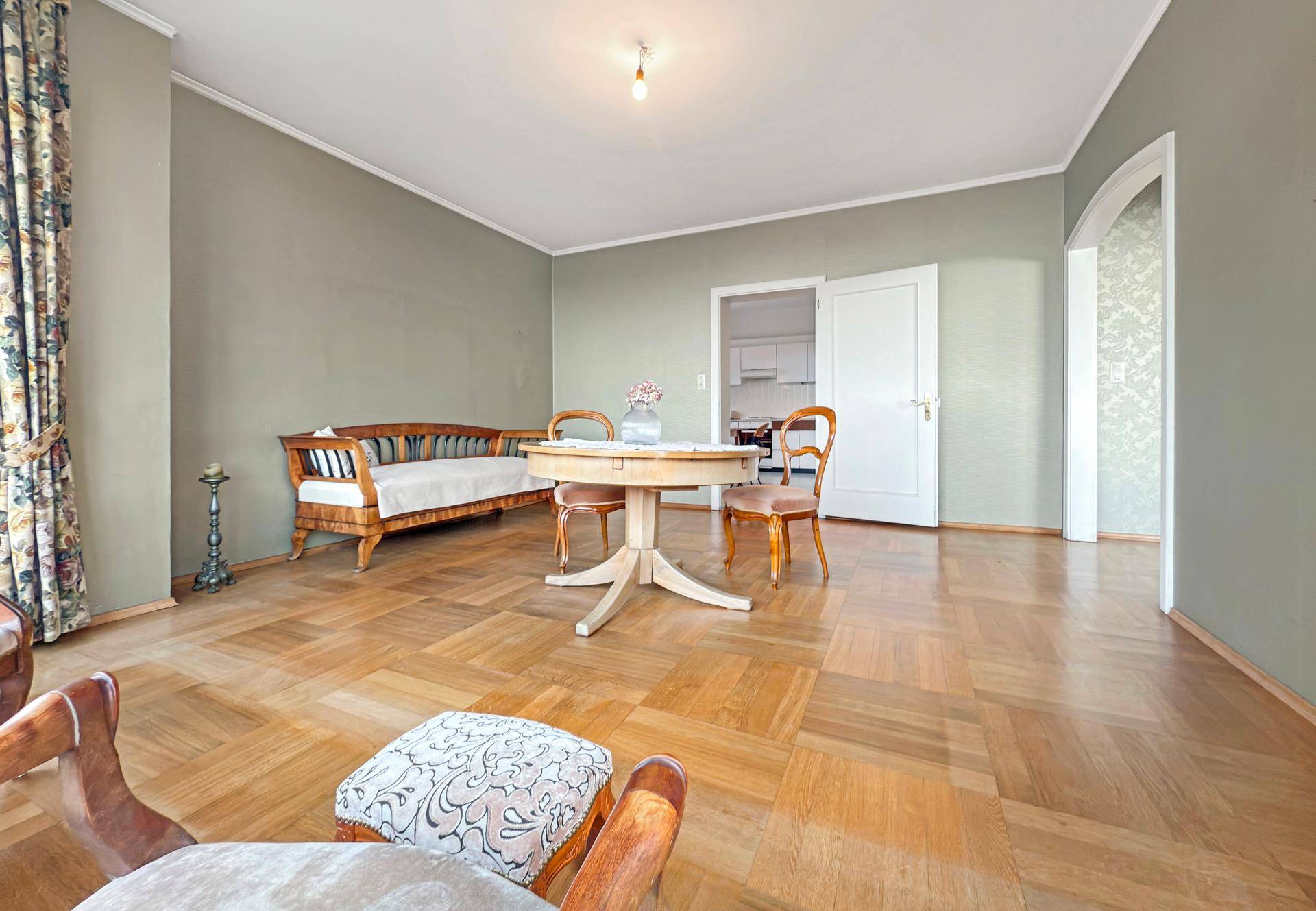 Klassischer Essbereich mit Holztisch, Stühlen und einer Holzbank, verbunden mit einem weiteren Raum.