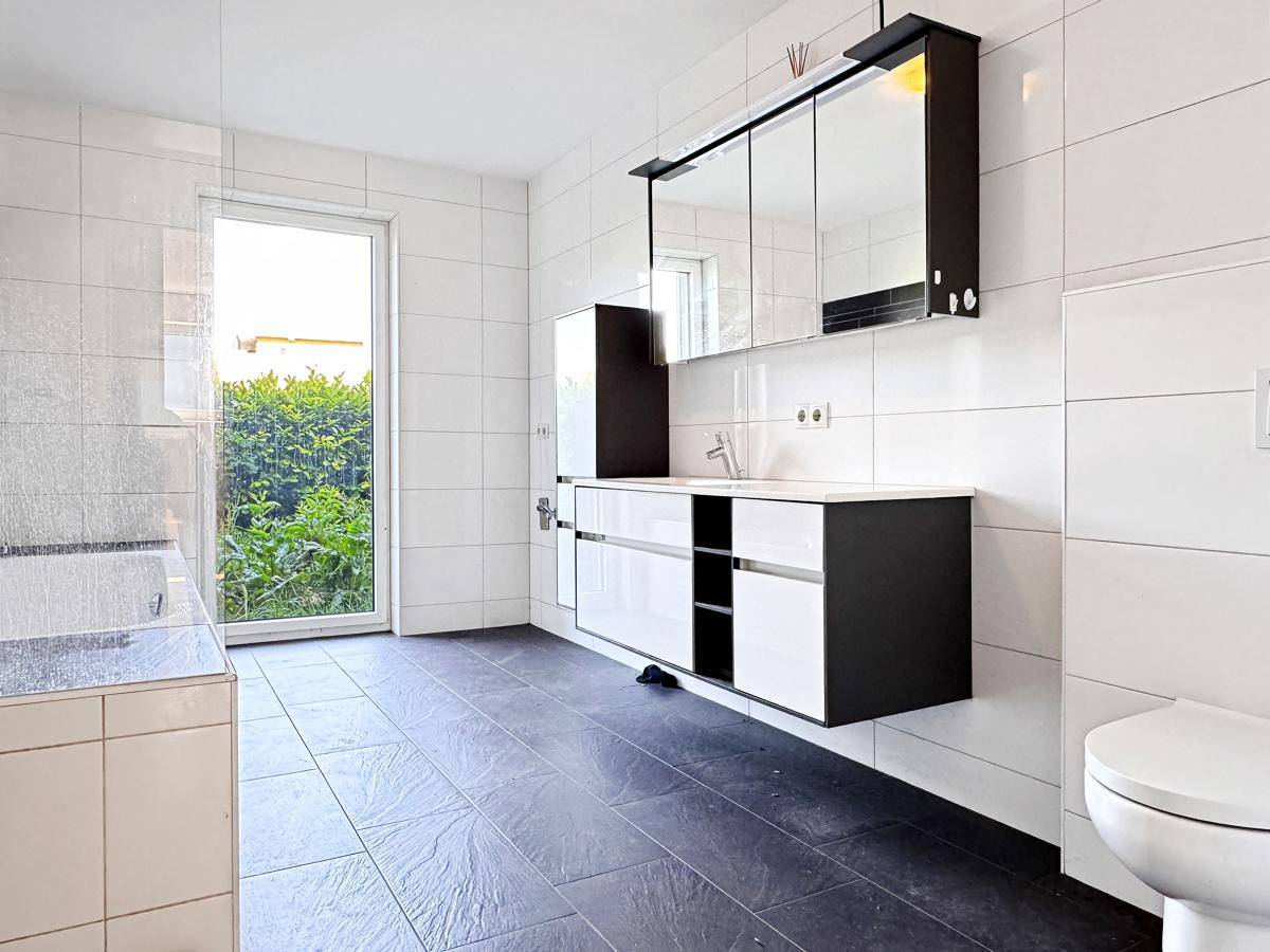 Modernes Badezimmer mit Waschtisch, Toilette und Fenster, bereit zur Fertigstellung.