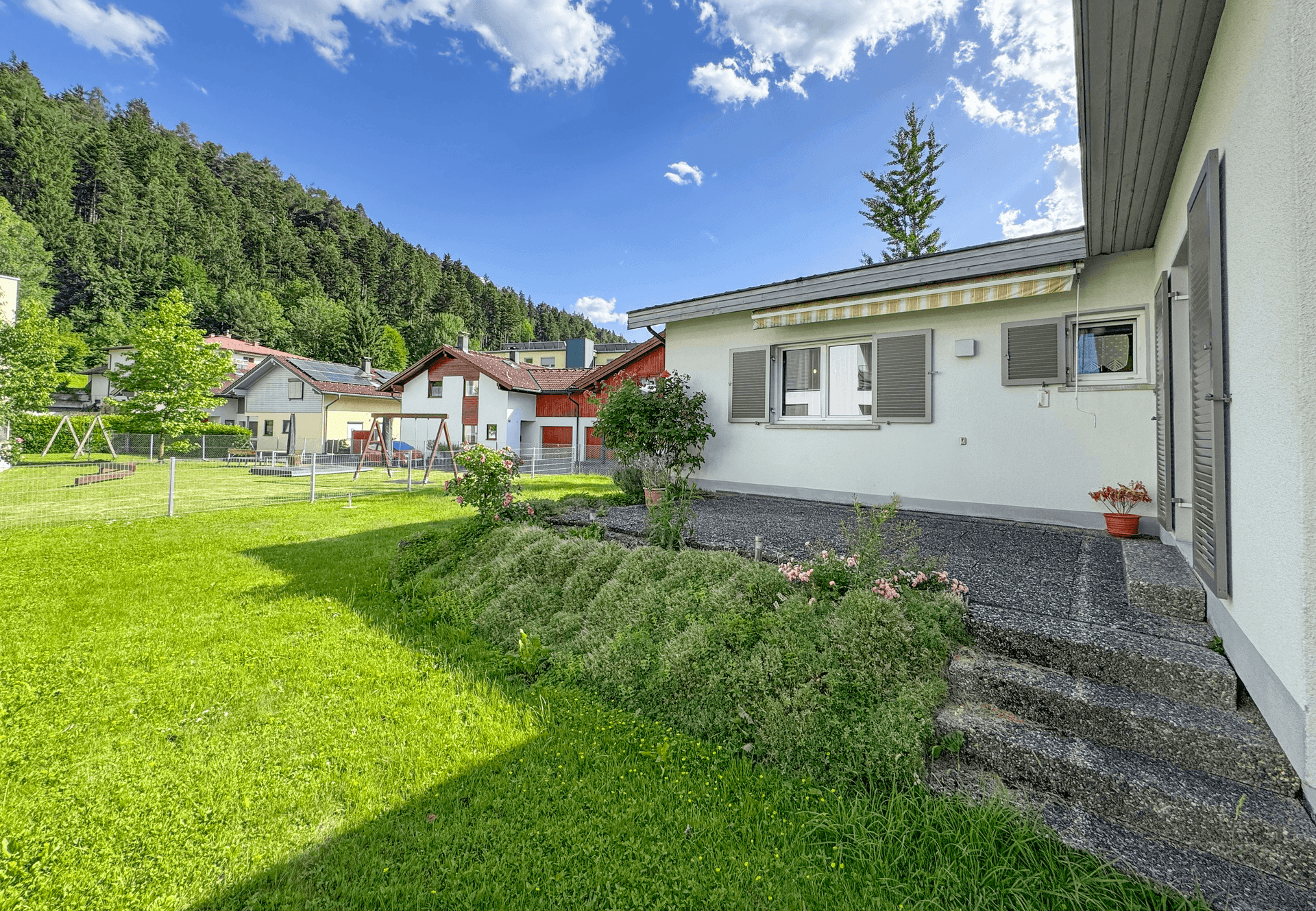 Großer Gartenbereich mit Rasenfläche und kleinen Beeten, angrenzend an die Hausfassade.