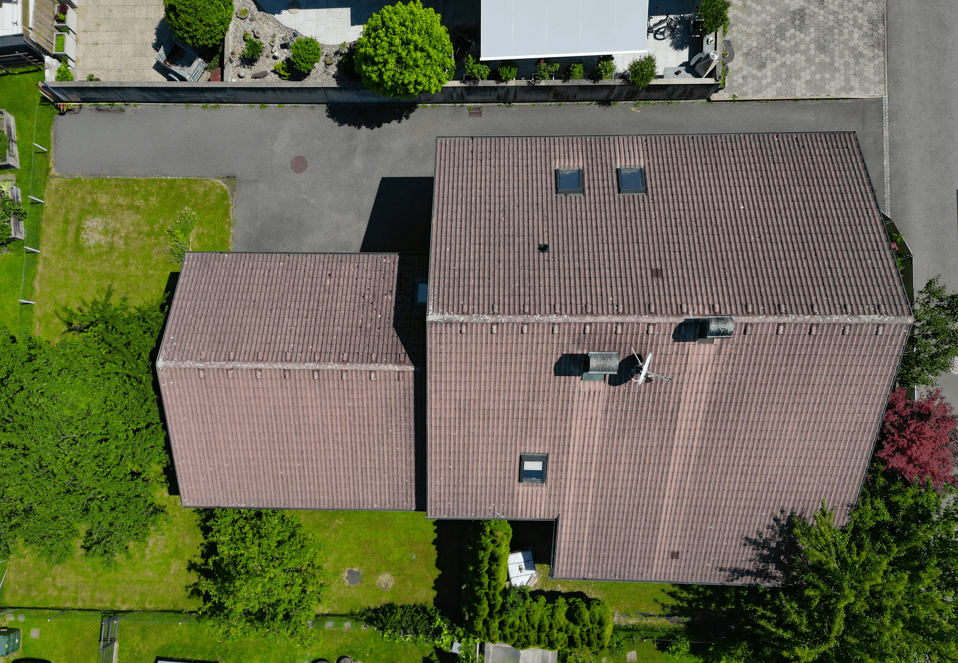 Dachansicht des Hauses mit zwei Dachfenstern und umliegendem Gartenbereich.
