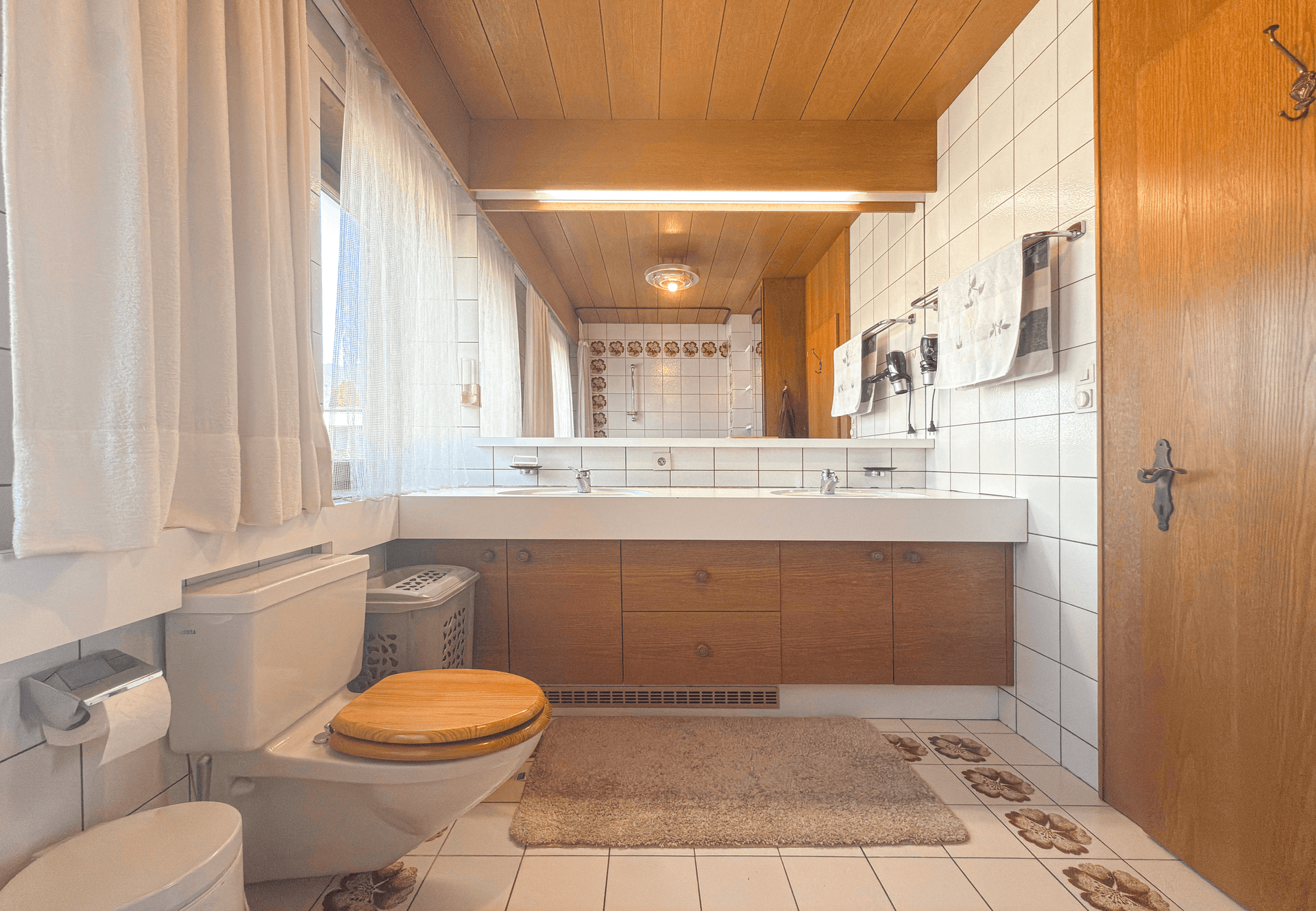 Badezimmer mit Doppelwaschbecken, Spiegelschrank und Fliesenboden in traditionellem Stil.