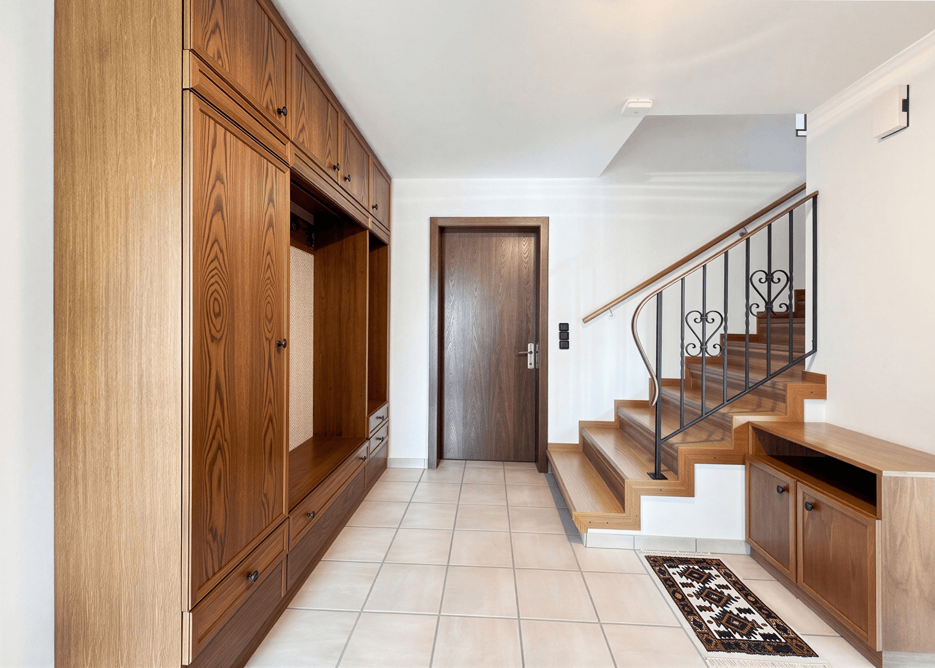 Eingangsbereich mit Einbauschränken, Treppe und Fliesenboden.