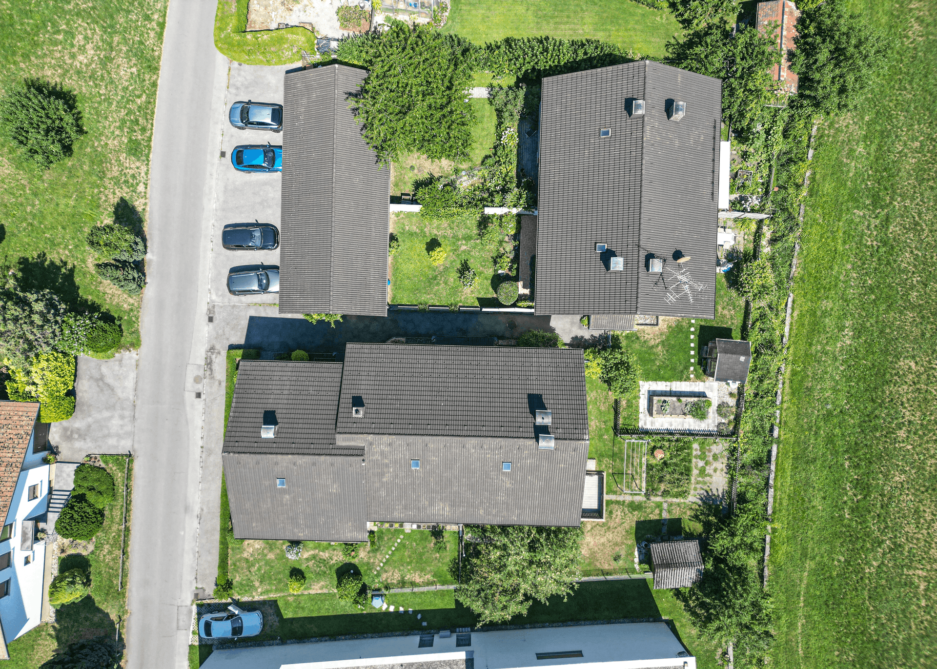 Senkrechte Luftaufnahme des Grundstücks mit Häusern, Gärten und Parkplätzen.
