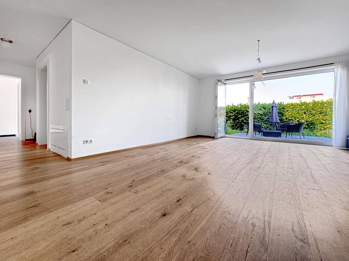 Heller Wohnbereich mit Holzboden und großen Schiebetüren zur Terrasse.