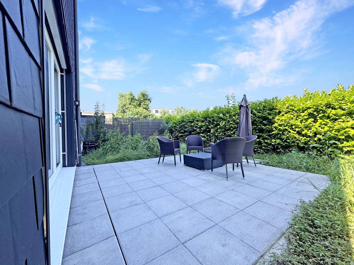 Gemütliche Terrasse mit Sitzgelegenheiten und umgebender Hecke, ideal zum Entspannen.