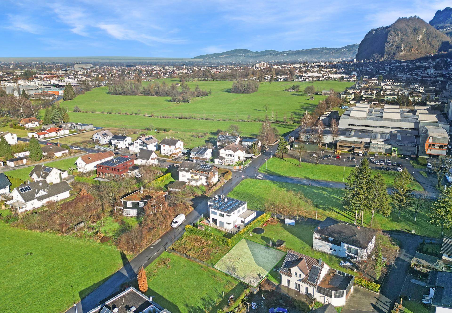 Weitläufige Luftaufnahme der Wohngegend mit Feldern und Bergen im Hintergrund.