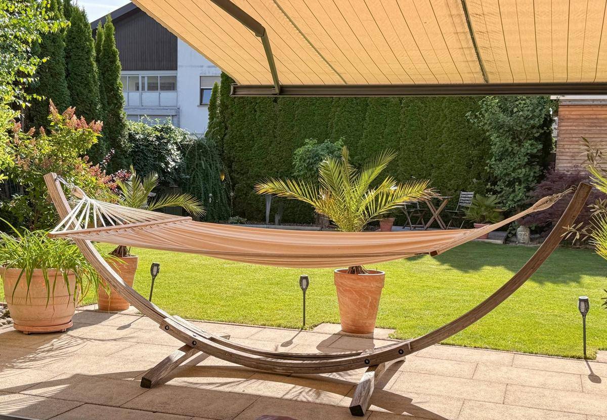 Entspannungsbereich auf der Terrasse mit Hängematte und Blick auf den grünen Garten.