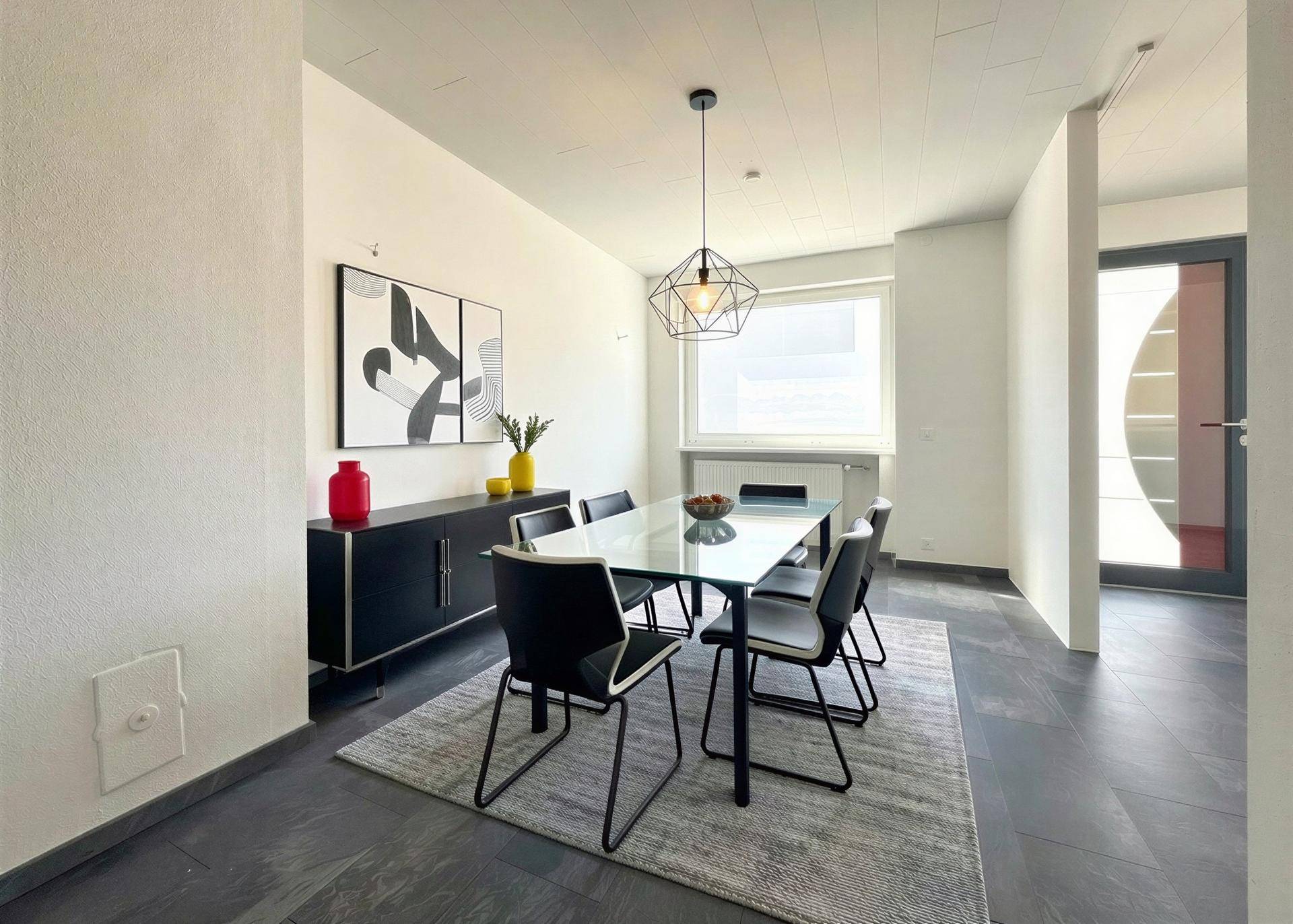Eleganter Essbereich mit modernem Tisch, dunklem Sideboard und viel Tageslicht.