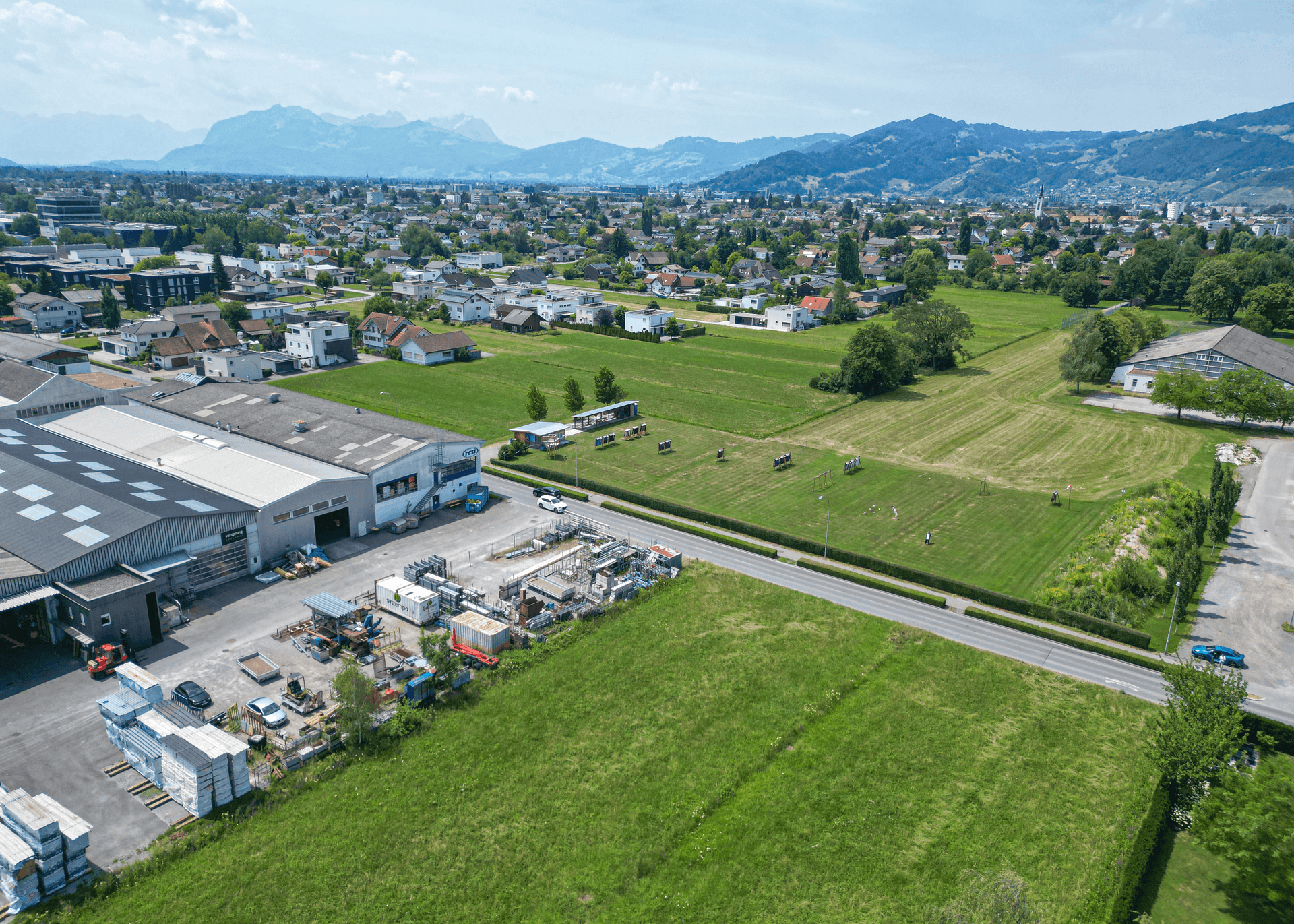 Umfassende Luftaufnahme der Umgebung mit dem Grundstück, Gewerbe, Wohngebieten und Stadtansicht im Hintergrund.