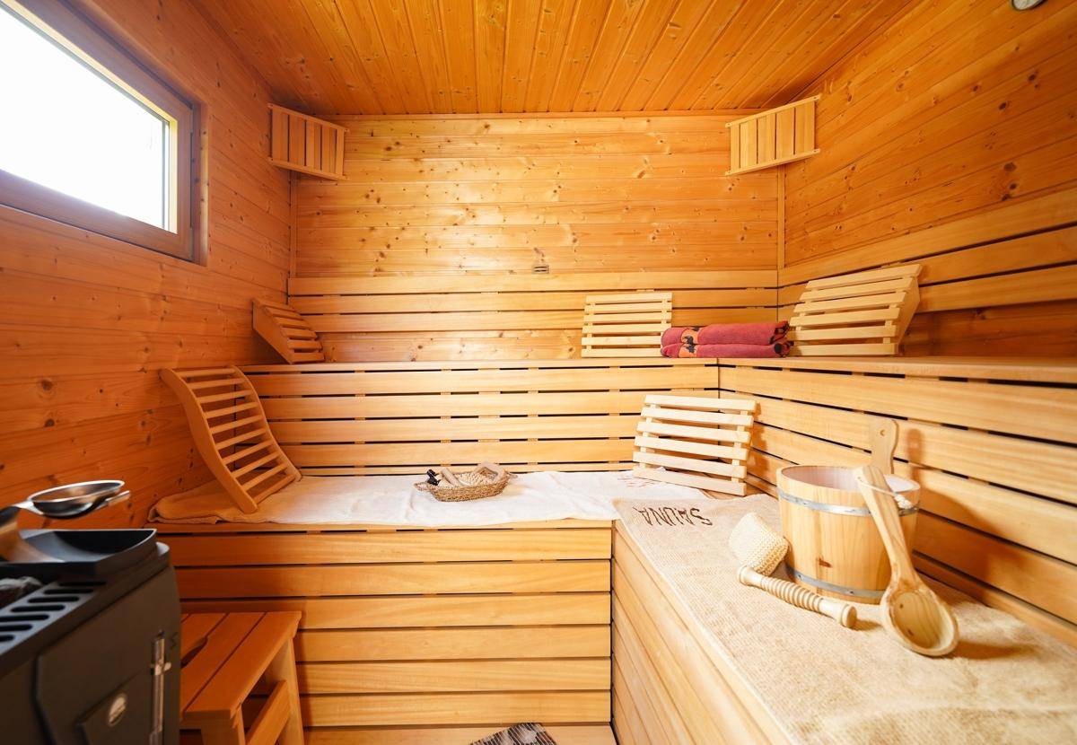 Gemütliche Holzsauna mit Bänken und traditionellem Saunaofen für Entspannung.