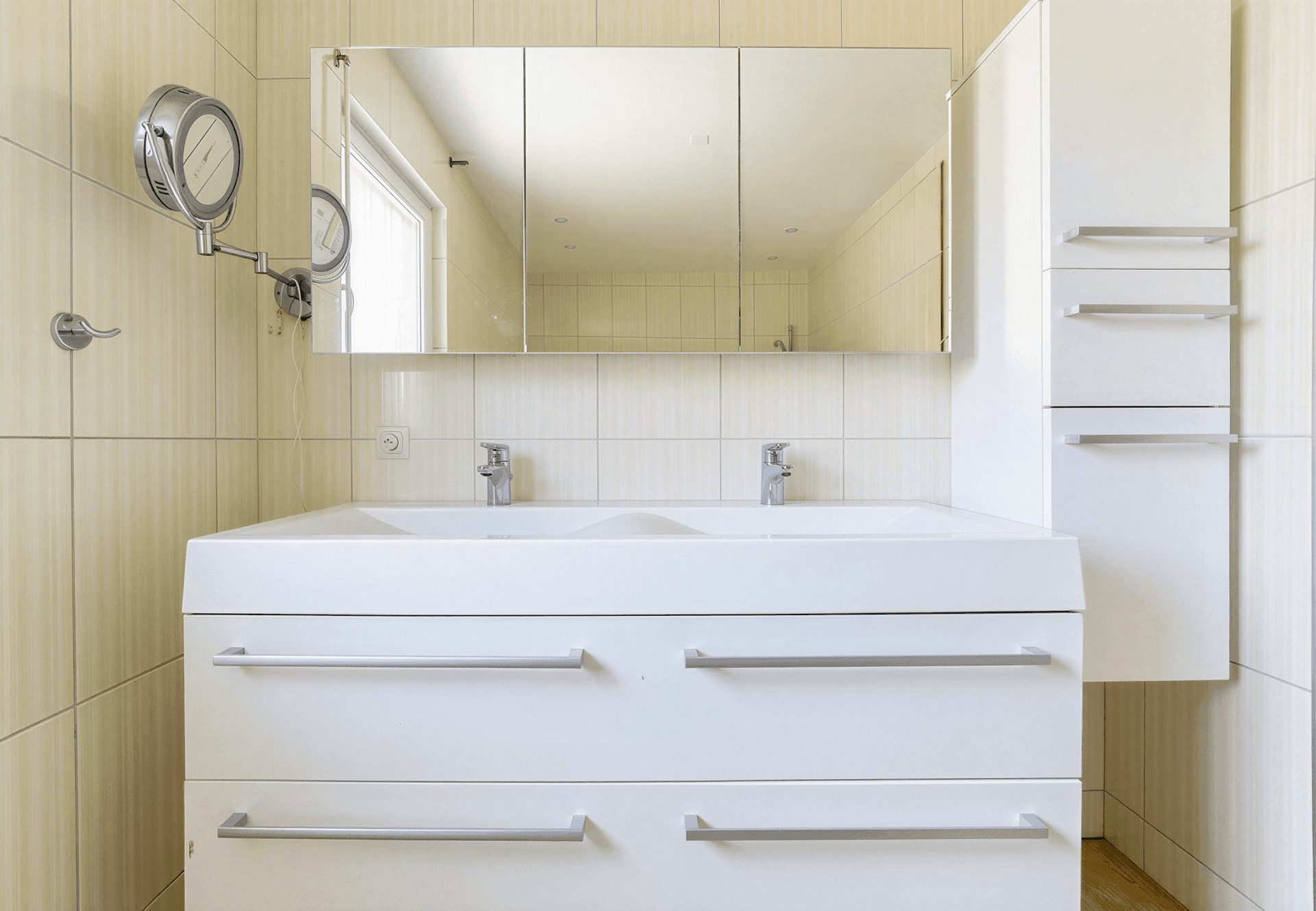 Modernes Badezimmer mit Doppelwaschbecken, großem Spiegelschrank und hellen Fliesen, sehr funktional.