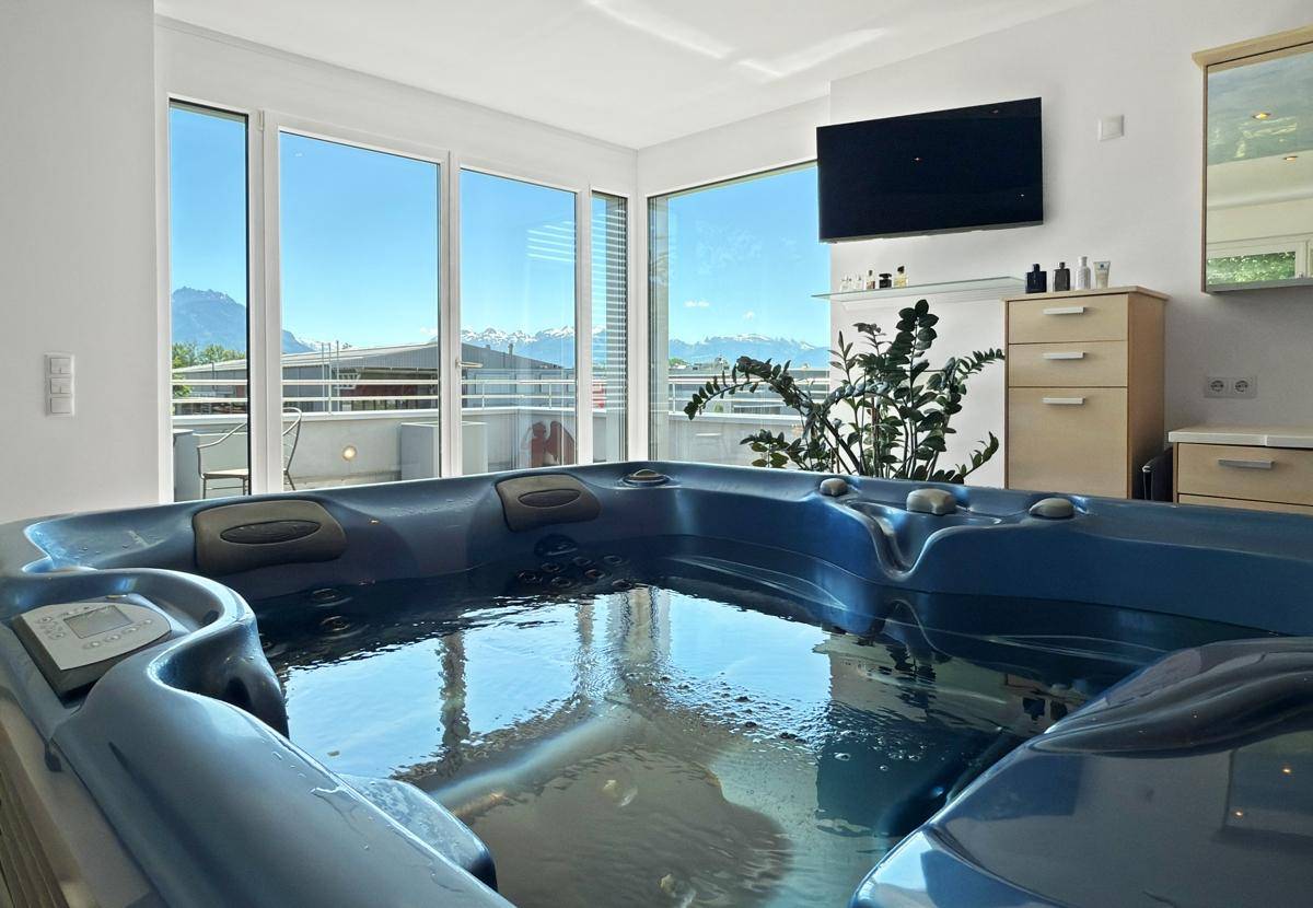 Luxuriöser Whirlpool-Bereich mit Bergblick durch große Fenster und Flachbildfernseher.