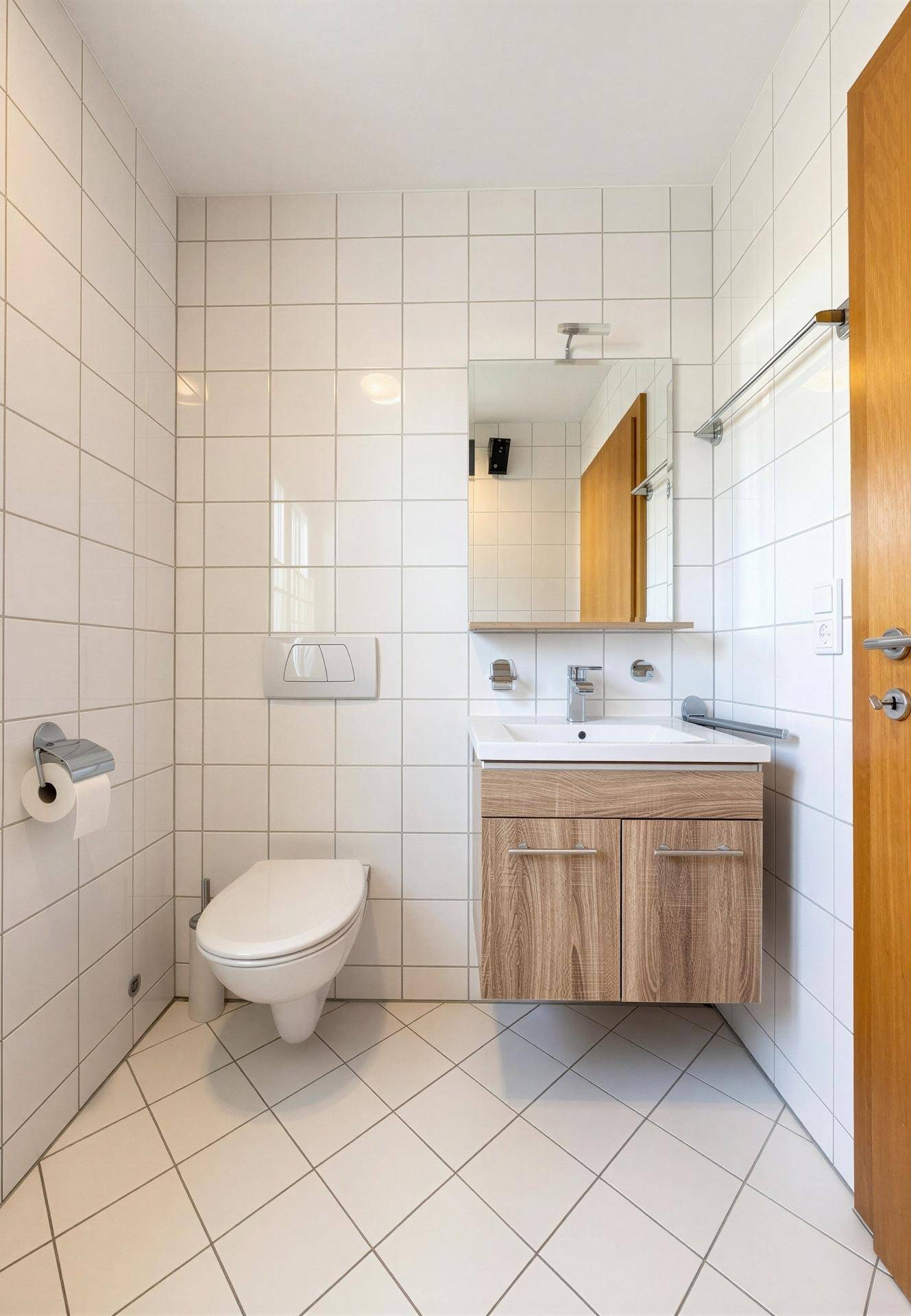 Kleines Badezimmer mit WC, Waschbecken und weißen Fliesen.