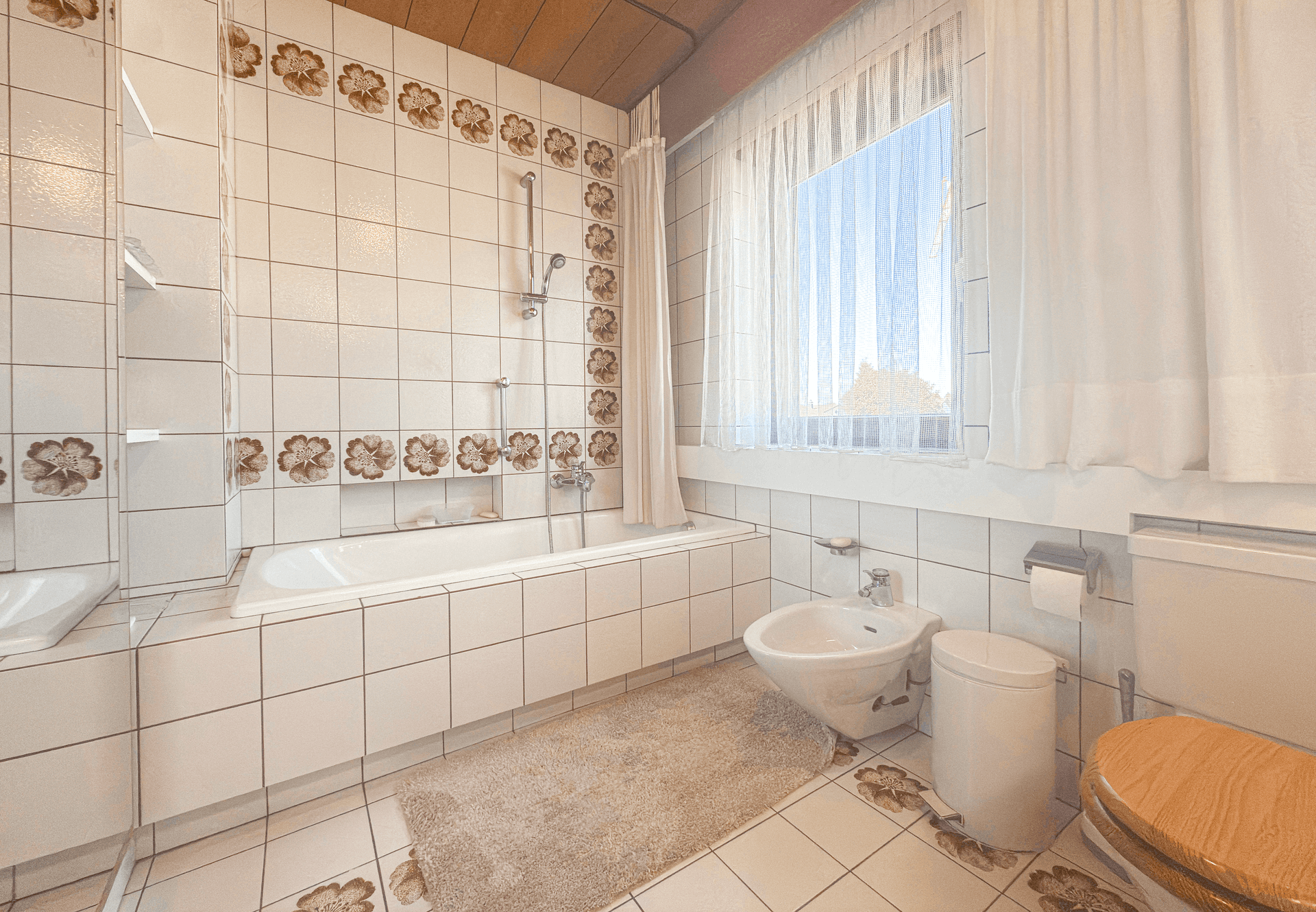 Badezimmer mit Badewanne, Bidet und Fenster für natürliche Belüftung.