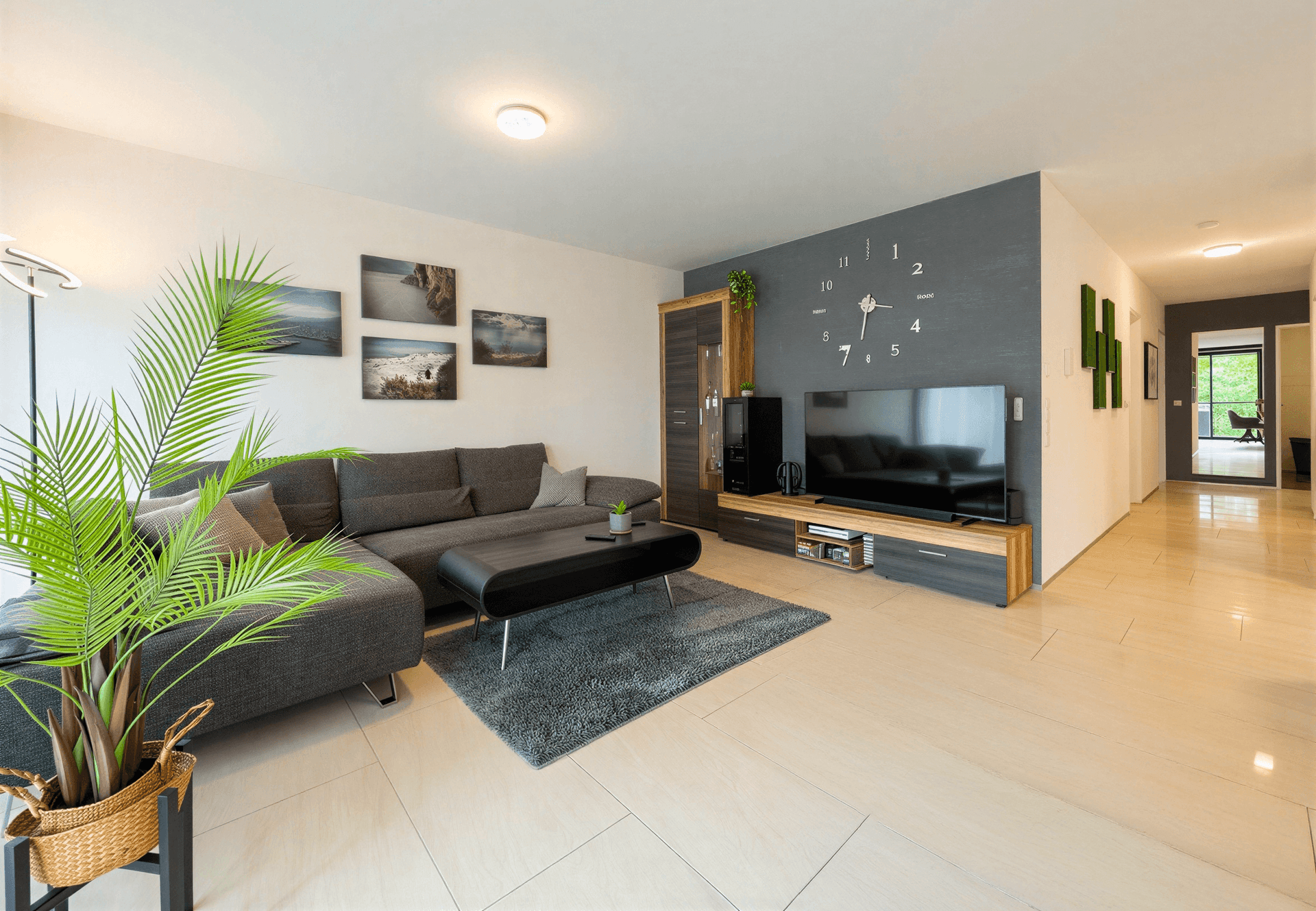 Geräumiges Wohnzimmer mit modernem Sofa, Fliesenboden und dekorativer Wandgestaltung.