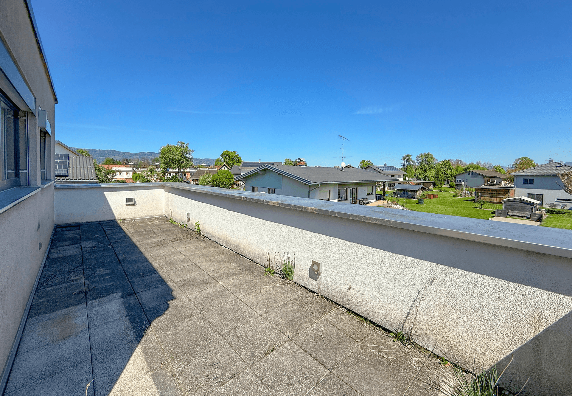 Weitläufige Dachterrasse mit Blick über die Nachbarschaft und grüne Umgebung.