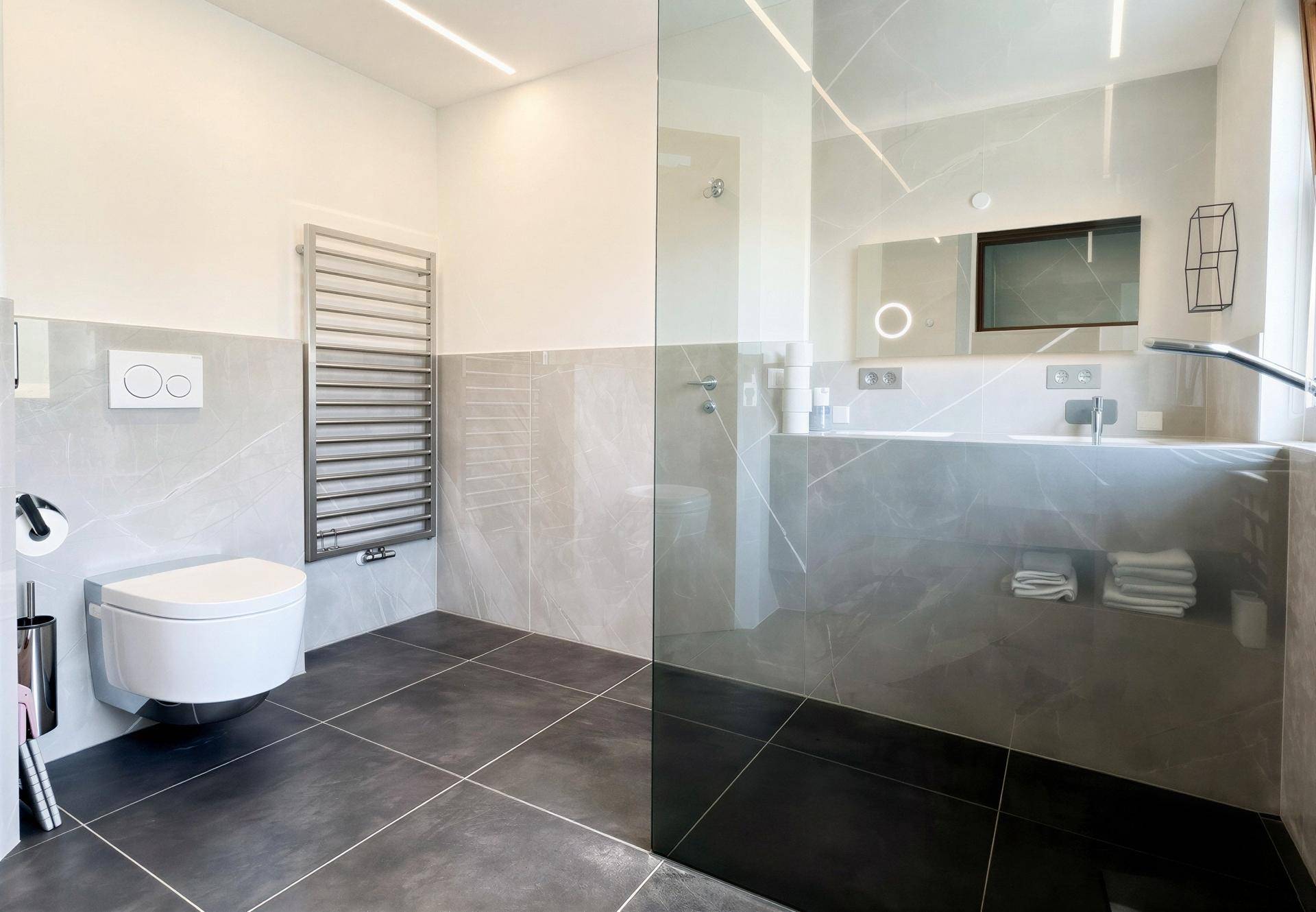 Elegantes Badezimmer mit wandhängendem WC, beheiztem Handtuchhalter und modernen Fliesen.