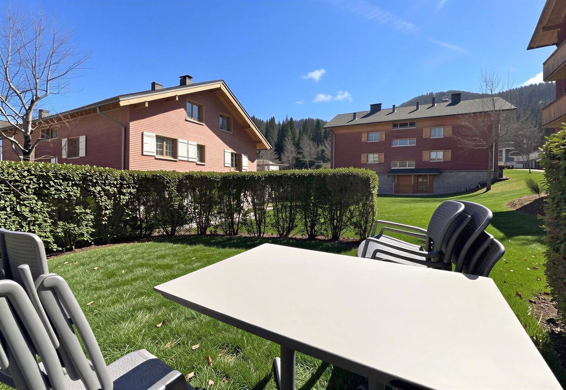 Gepflegter Gartenbereich mit Sitzgelegenheiten und Blick auf die umliegenden Gebäude.