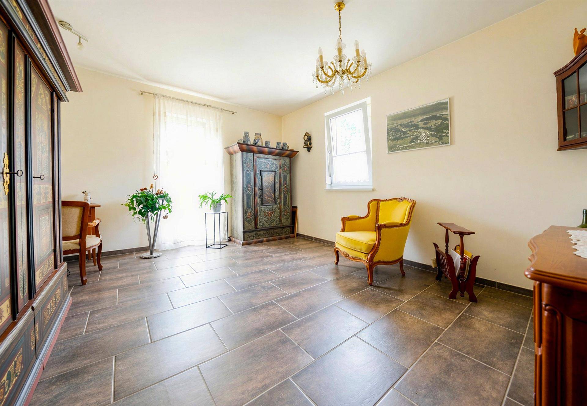 Geräumiges Zimmer mit traditionellen Holzmöbeln, Fliesenboden und Kronleuchter.