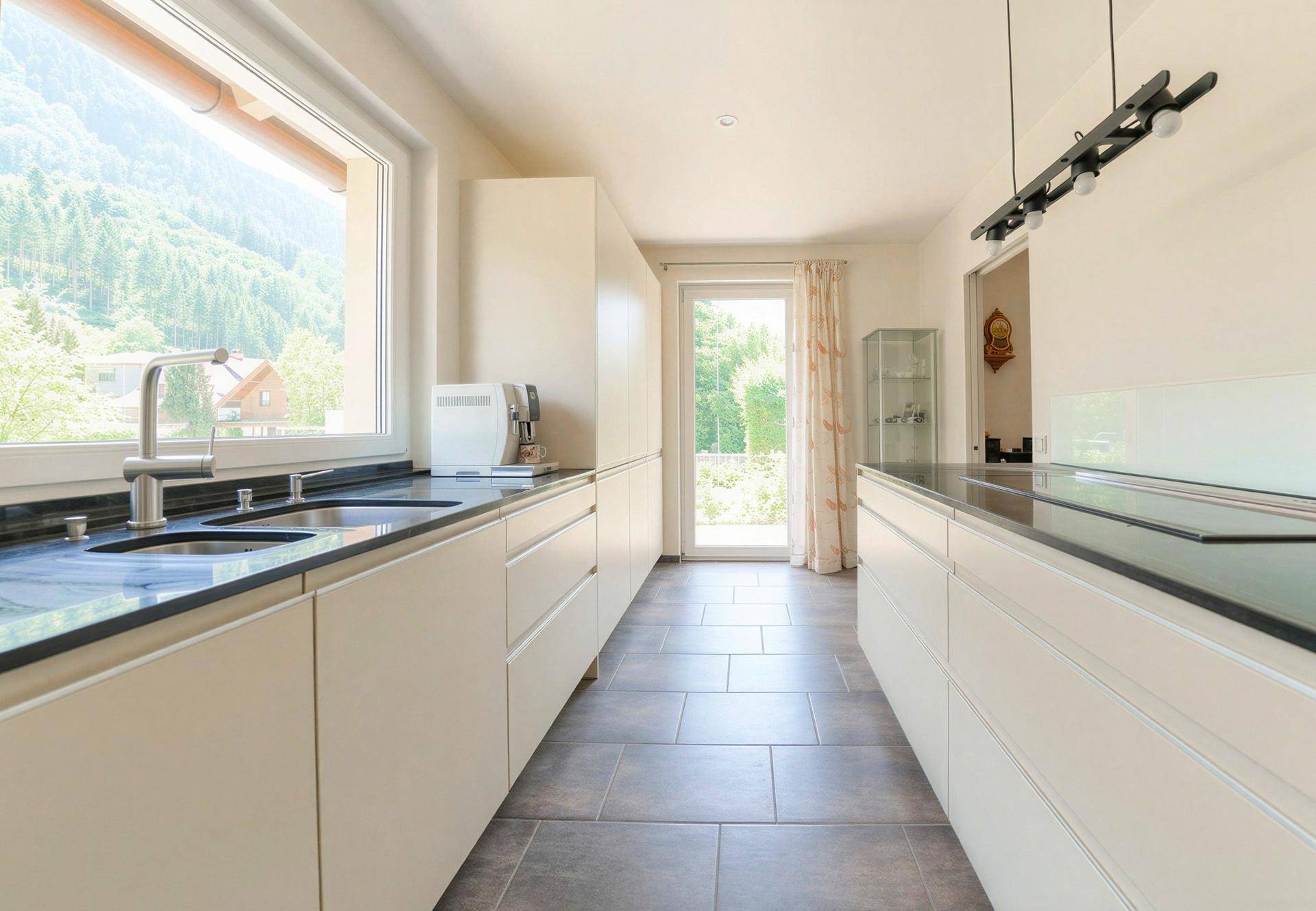 Helle Küche mit Bergblick, modernen Armaturen und Zugang zum Außenbereich.