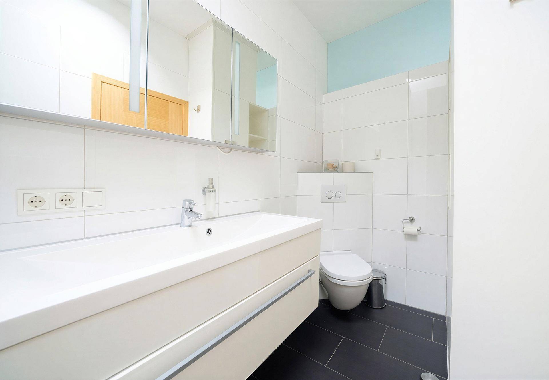 Helles WC mit modernem Waschbecken, wandhängendem WC und Spiegelschrank.