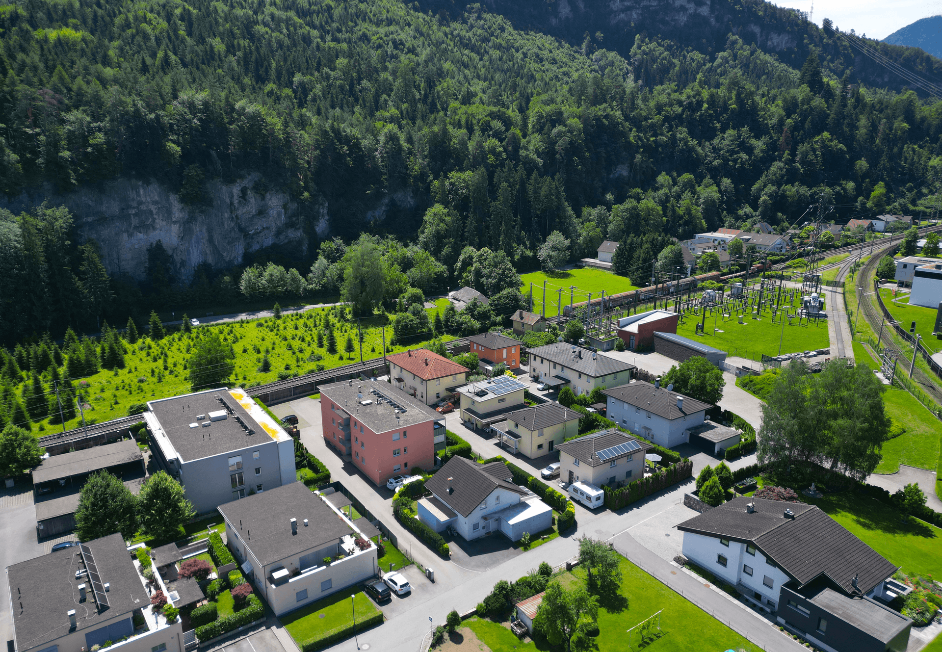 Panoramablick auf die Wohnsiedlung mit grünen Flächen, Wald und Bahngleisen, sehr weitläufig.