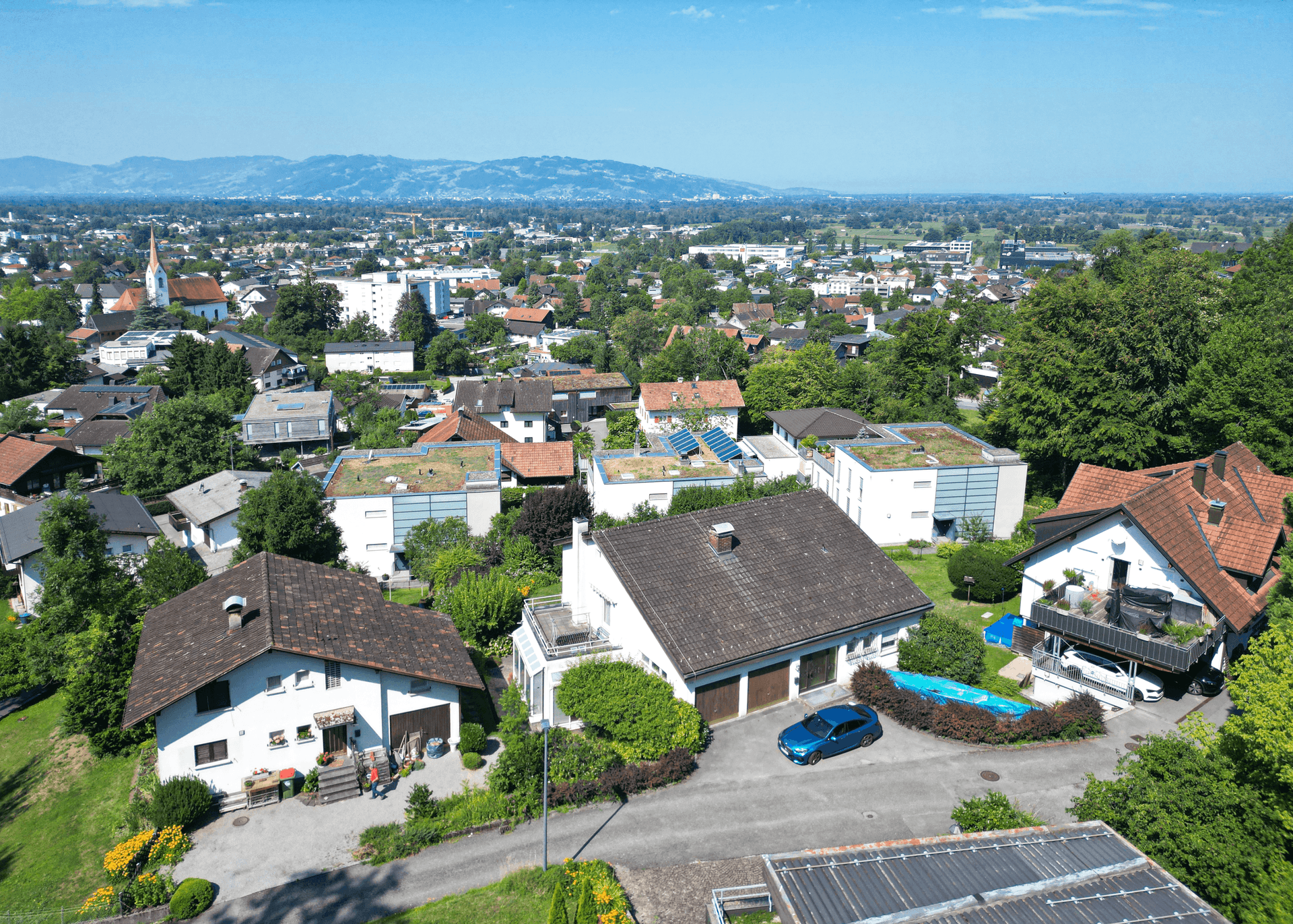 Luftaufnahme einer Wohnsiedlung mit Häusern, Gärten und Blick auf die weitere Umgebung.