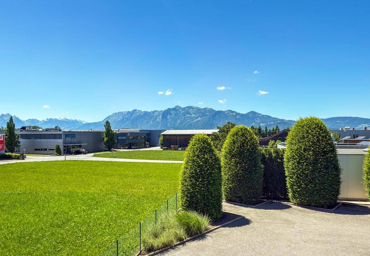 Weitläufige Grünfläche mit gepflegten Hecken und einem beeindruckenden Bergblick.