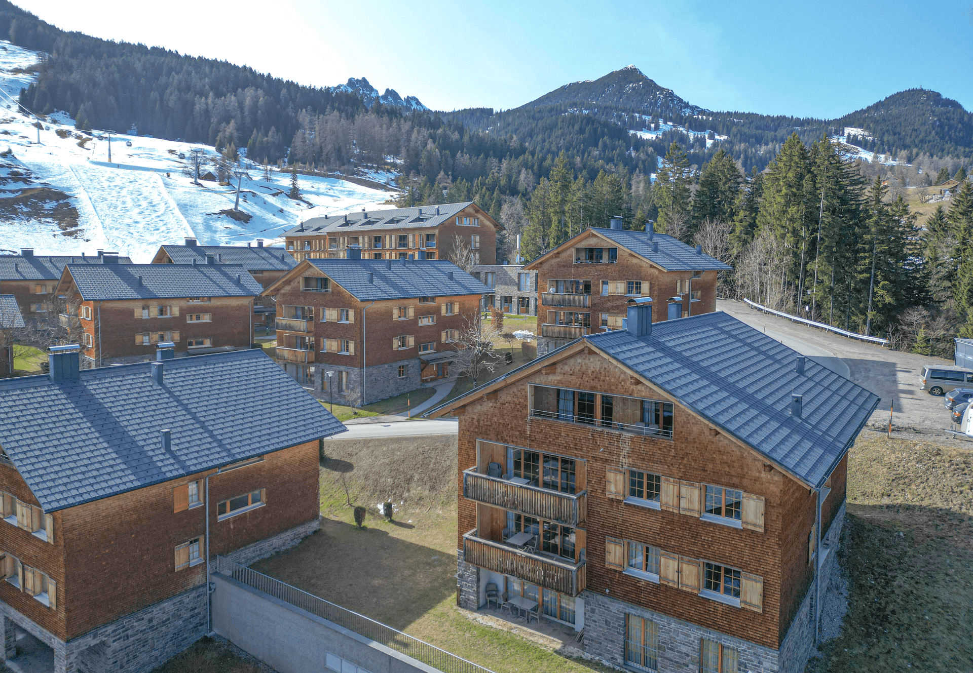 Charmante Holzhäuser mit Schindeldächern in einer grünen Berglandschaft, ideal für Erholung.