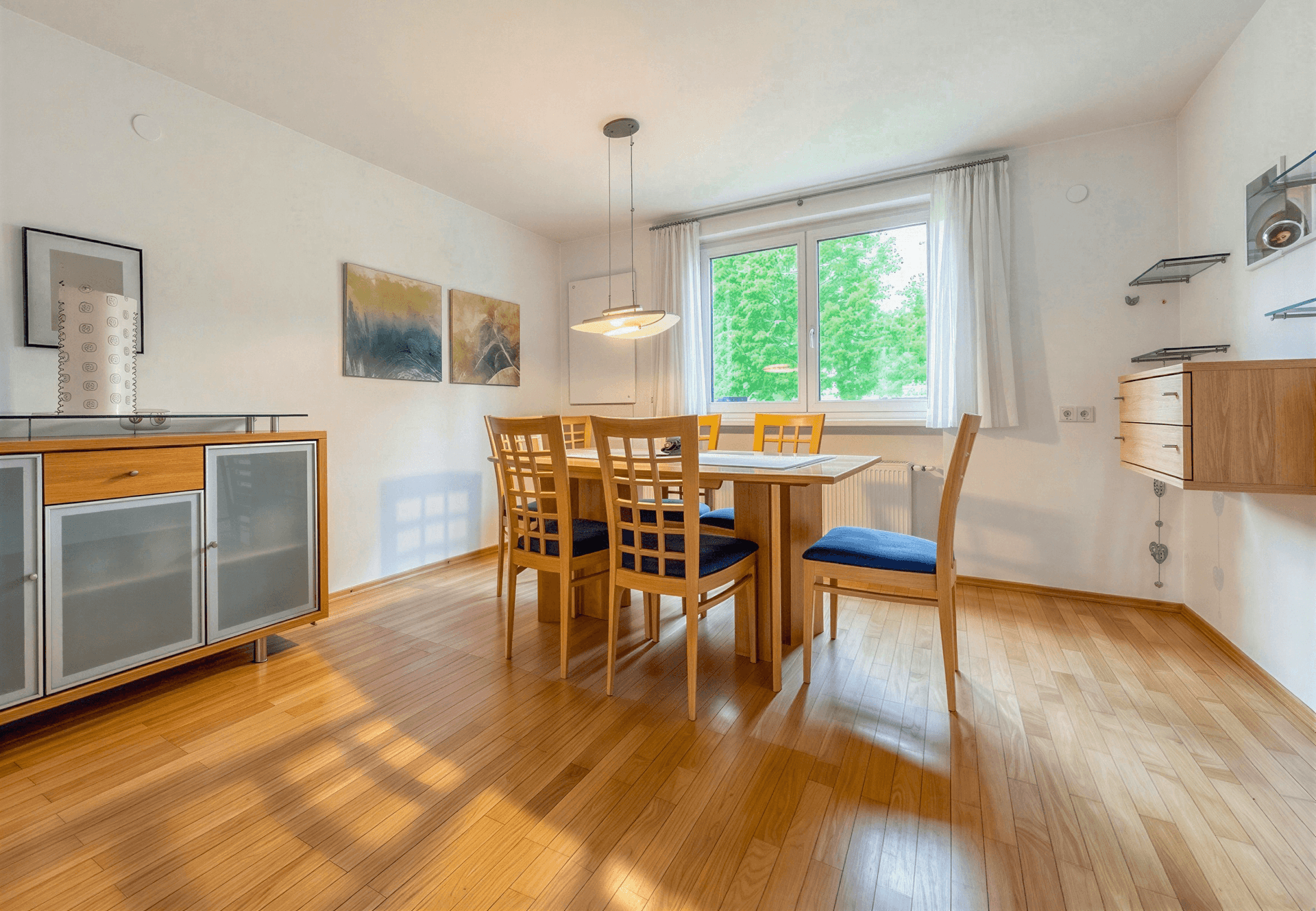 Heller Essbereich mit Holztisch und Stühlen, passendem Sideboard und Parkettboden.