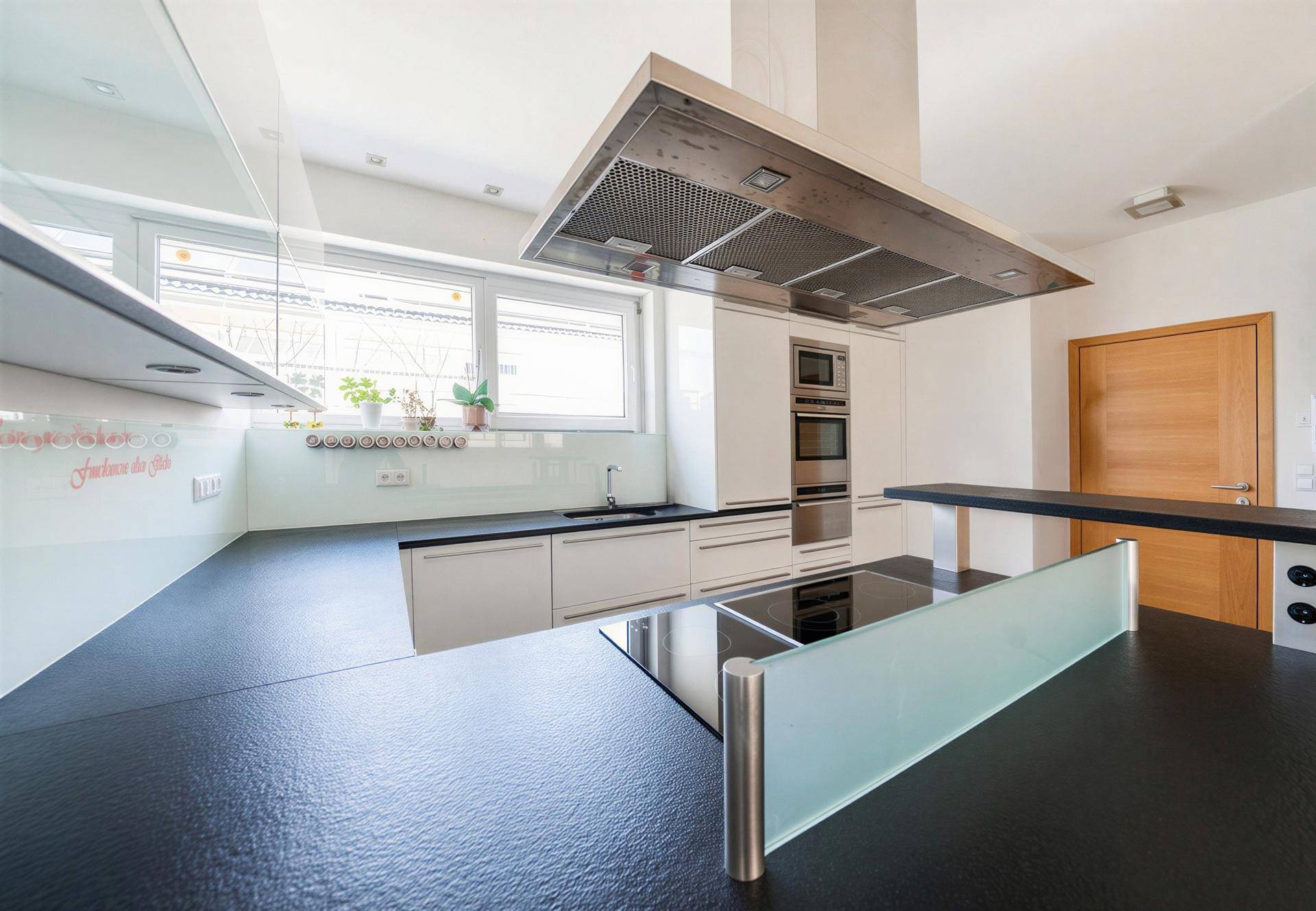Helle, moderne Küche mit Kochinsel, Induktionskochfeld und hochwertigen Einbaugeräten.