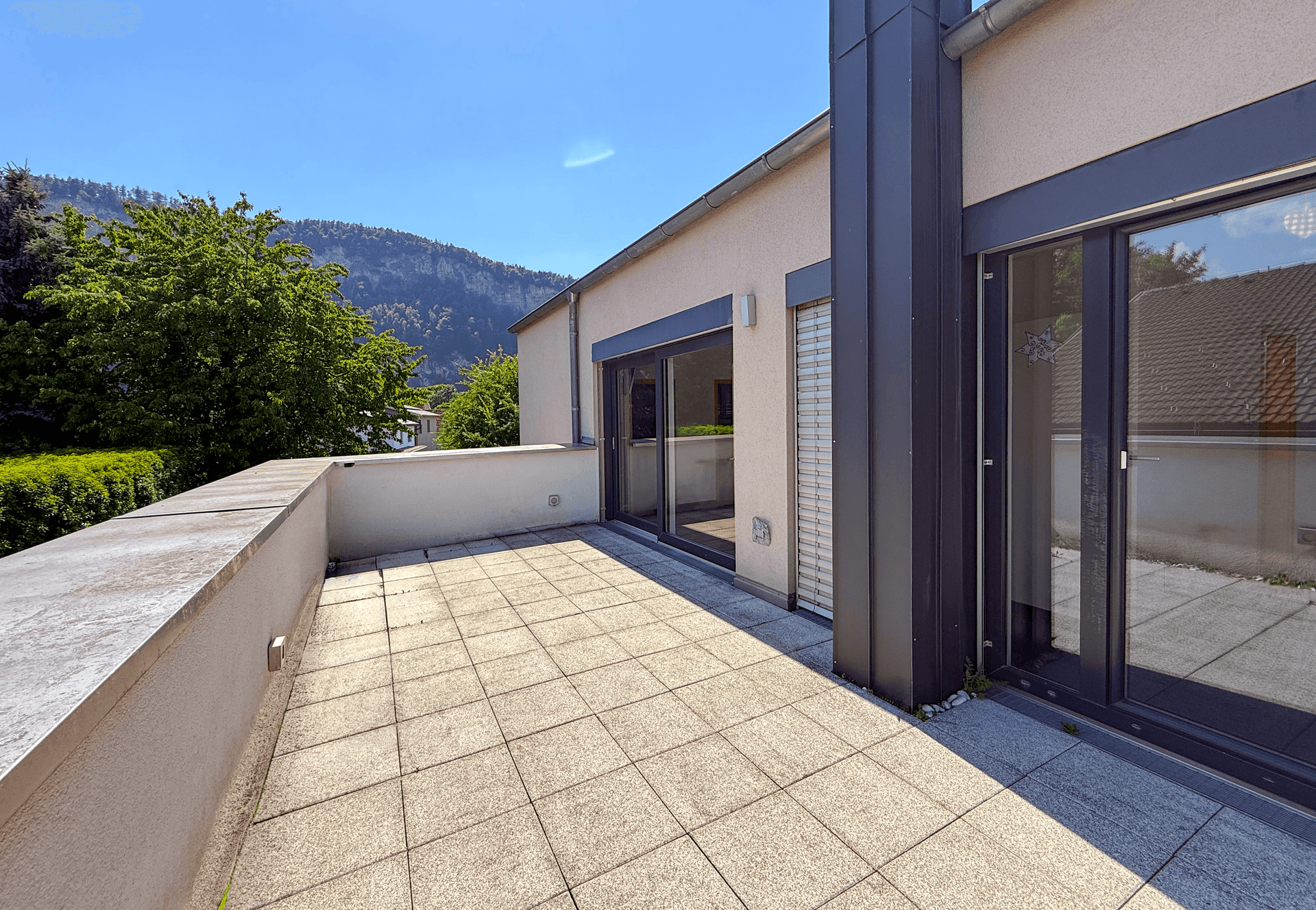 Geräumige Dachterrasse mit Fliesenboden und weitem Blick auf die Umgebung.
