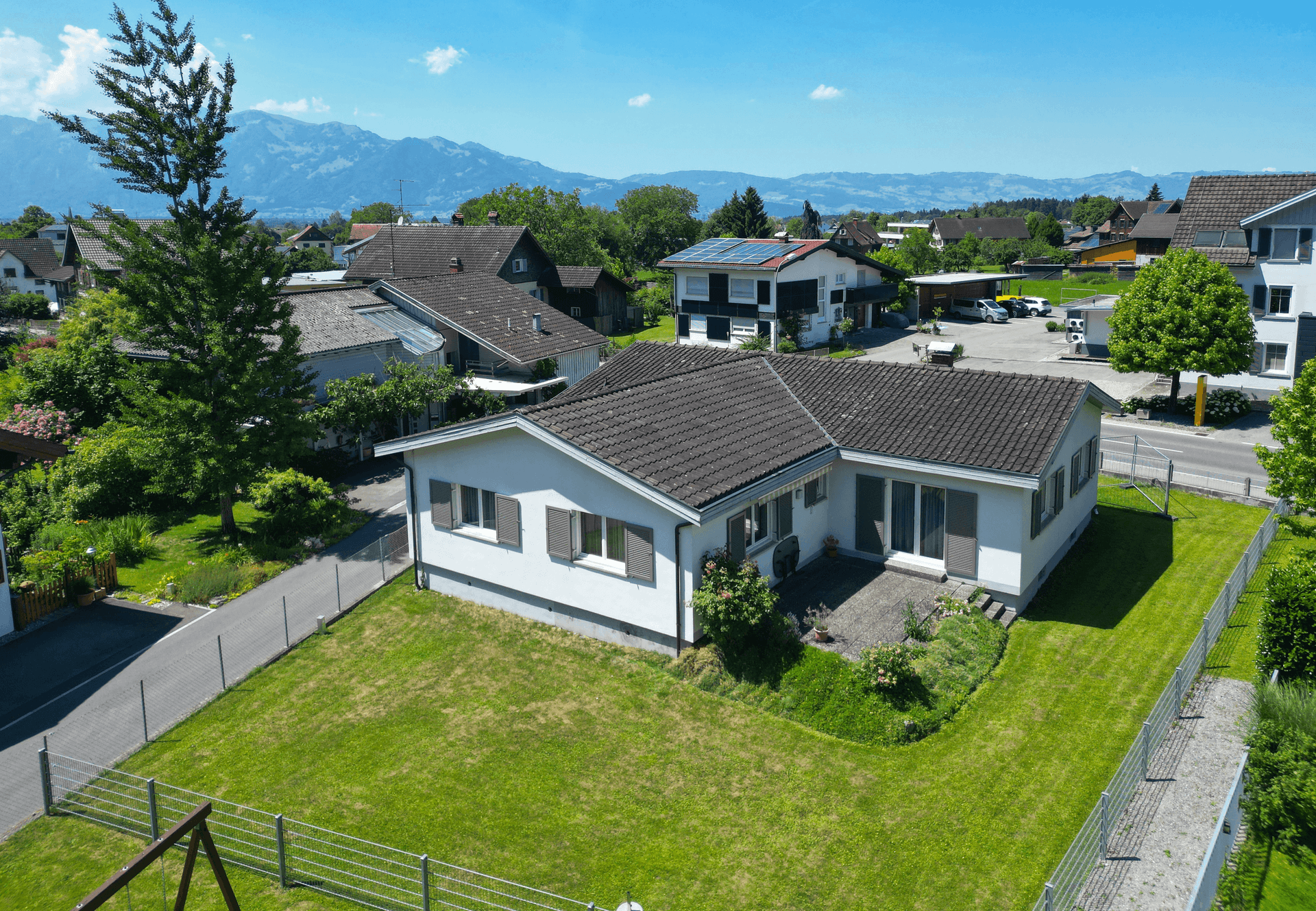 Luftaufnahme des Hauses mit Garten, gepflastertem Bereich und weitem Blick auf die Berglandschaft.