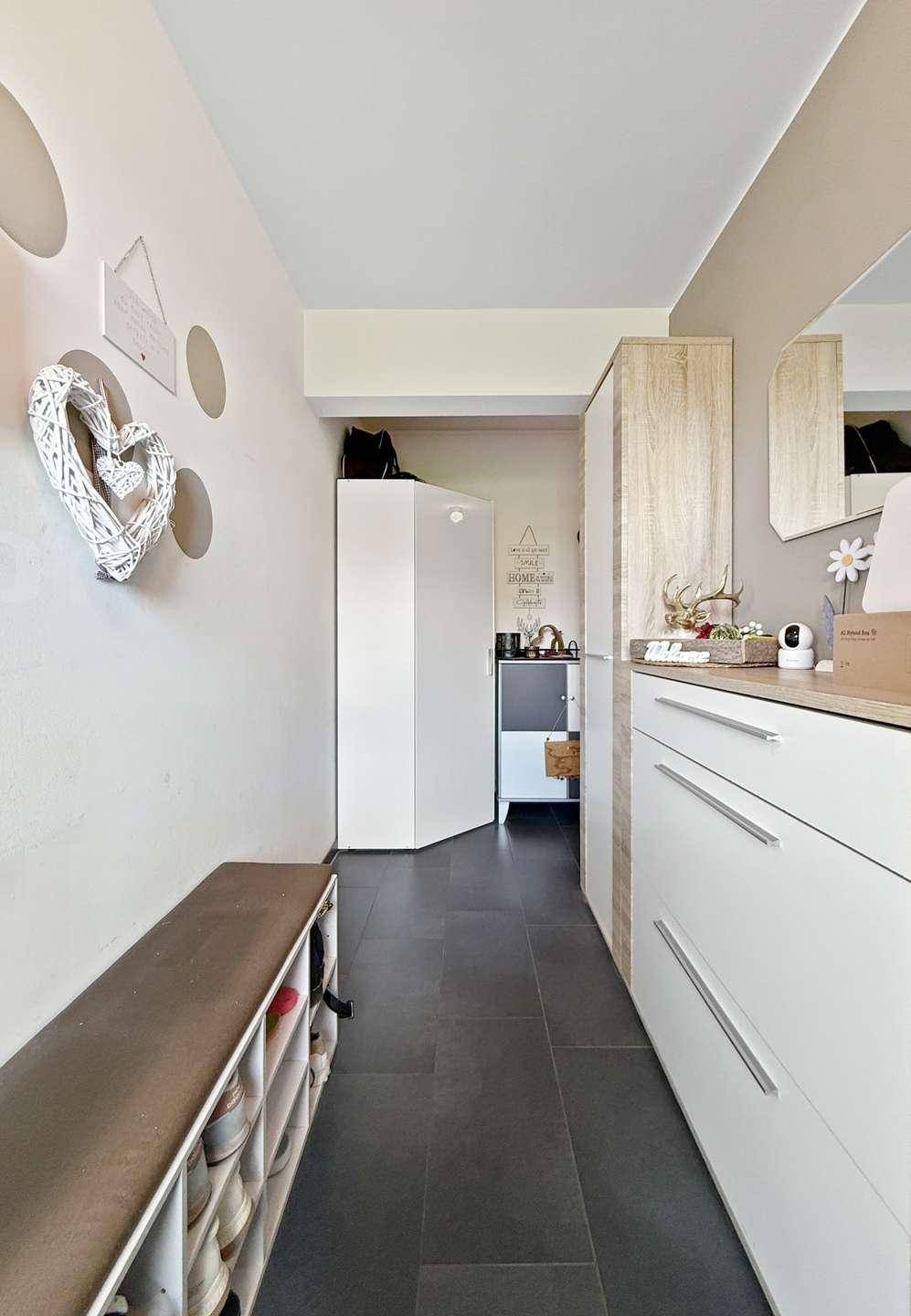 Heller Flur mit dunklen Fliesen, praktischer Garderobe und integriertem Stauraum.
