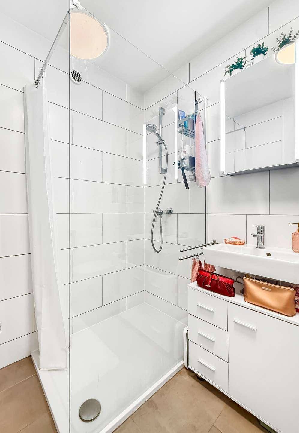 Helles Badezimmer mit begehbarer Dusche, Waschbecken und Spiegelschrank.