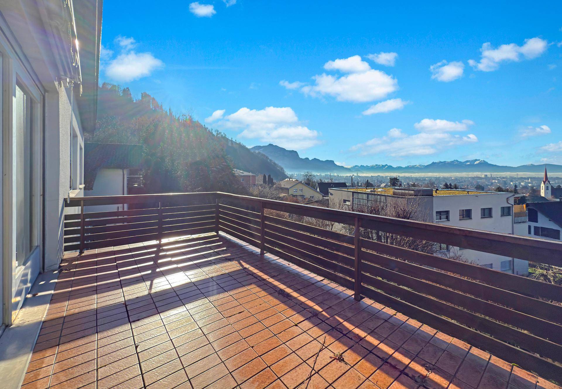Sonniger Balkon mit Panoramablick auf die umliegende Berglandschaft und das Tal.