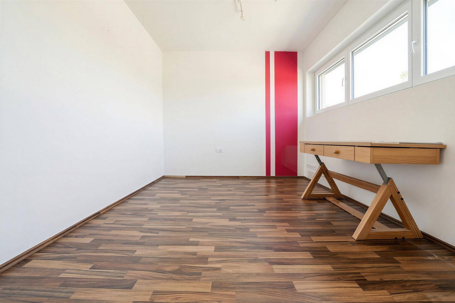 Heller Arbeitsraum mit Laminatboden, Fenster und modernem Holzschreibtisch.