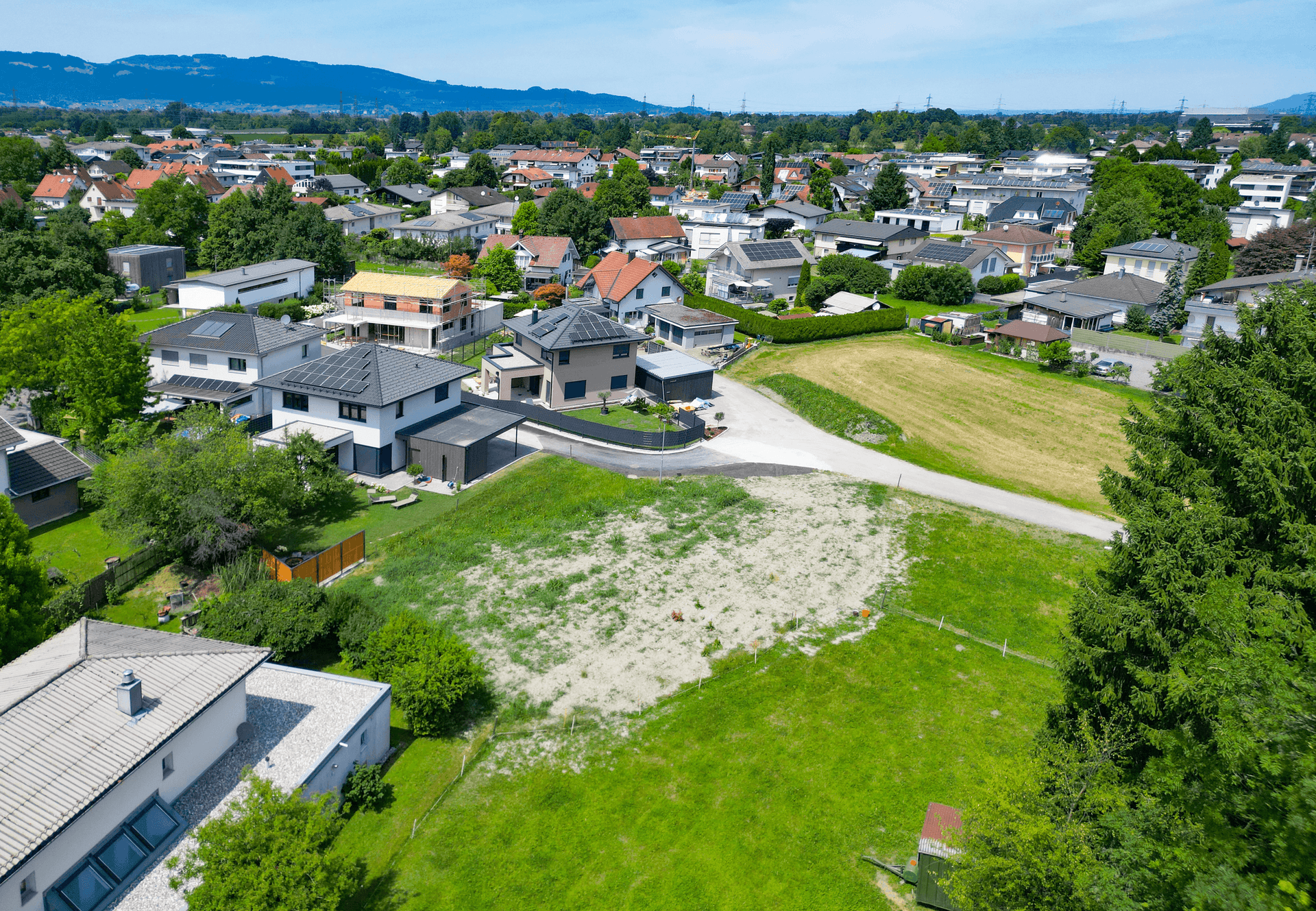 Panoramablick aus der Luft auf ein unbebautes Grundstück in einer dicht besiedelten Wohngegend.